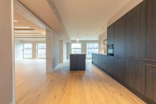 Modern open-plan kitchen and living area with wooden flooring and large windows on Rokin street.