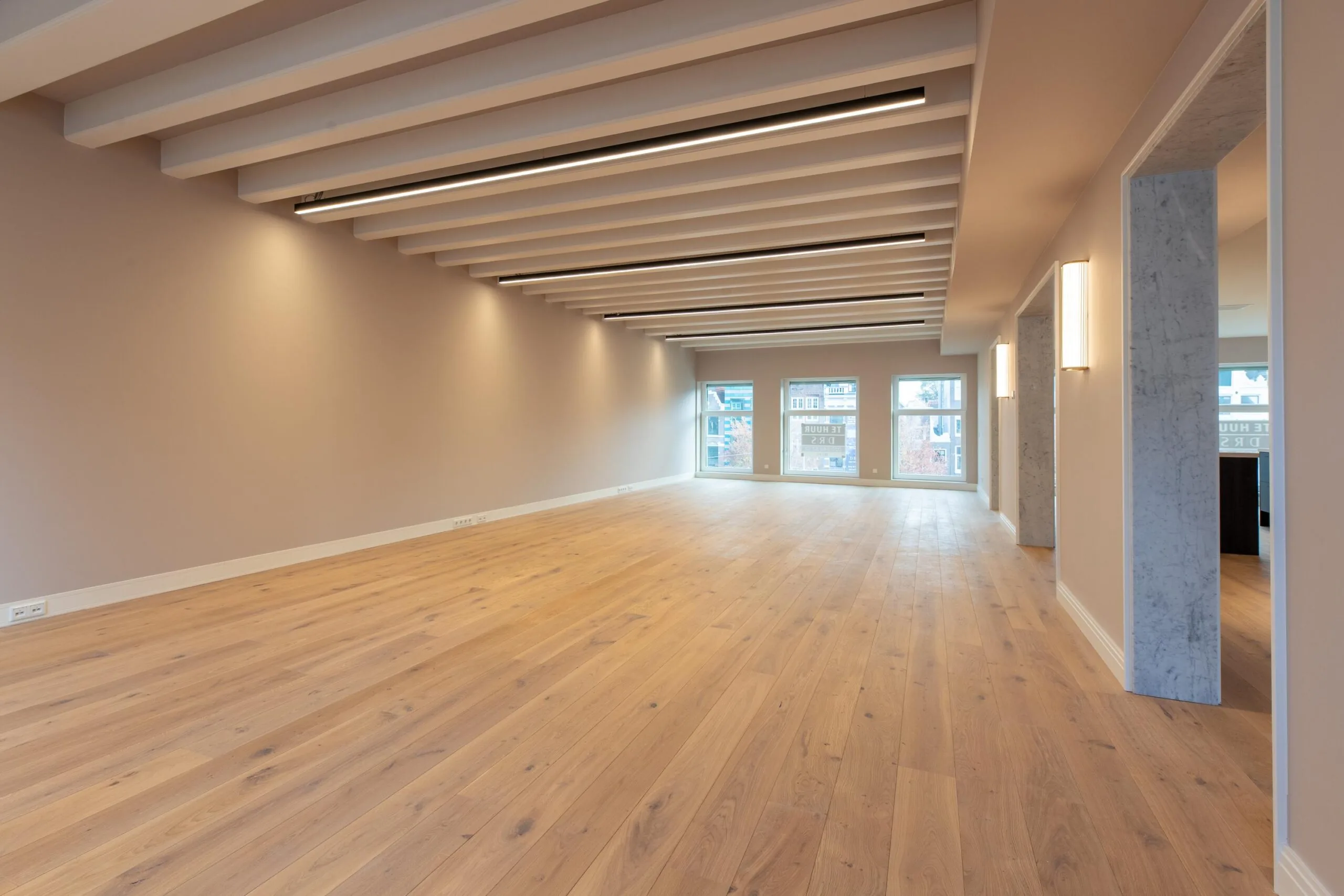 Modern, unfurnished office space with wooden flooring and large windows on Rokin in Amsterdam.