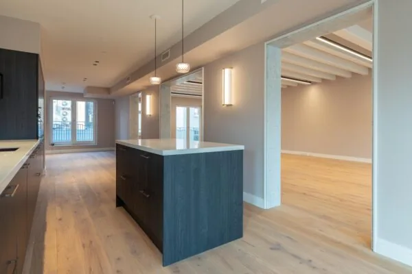 Modern open-plan apartment at Rokin with wooden flooring, a dark kitchen island, and large windows allowing natural light.