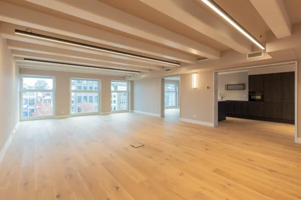 Modern open-plan apartment on Rokin with large windows, wooden flooring, and a sleek built-in kitchen.