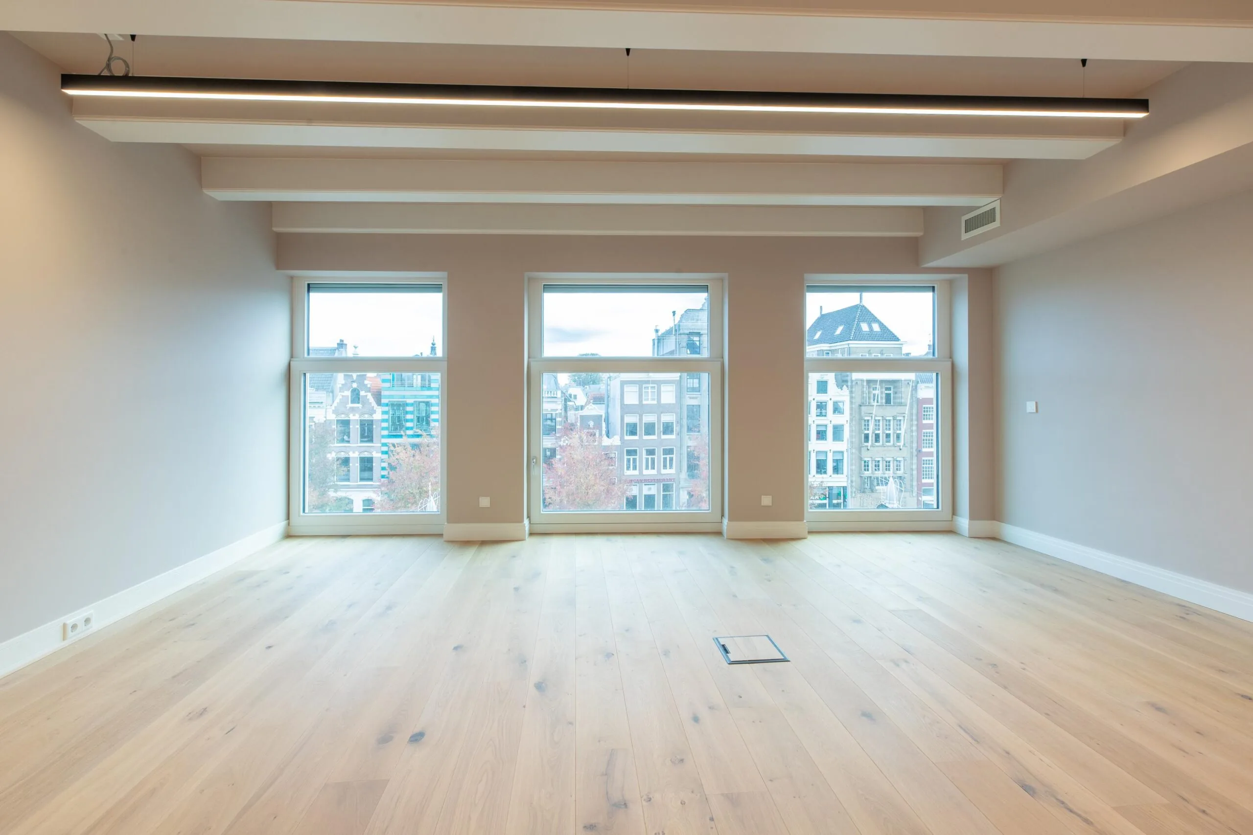 Bright, empty room with large windows overlooking historic buildings on Rokin street in Amsterdam.