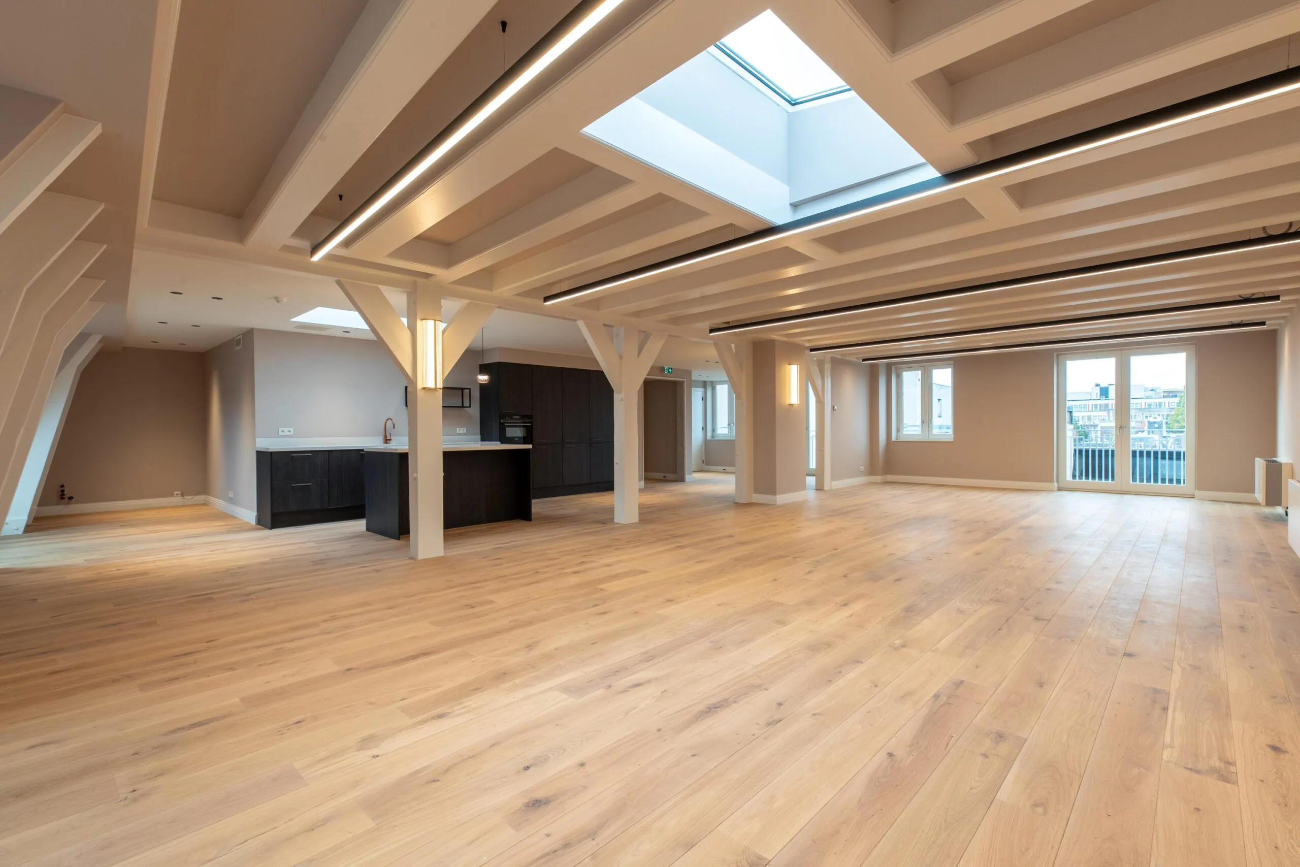 Spacious modern apartment on Rokin with wooden flooring, large windows, exposed beams, and a central skylight.