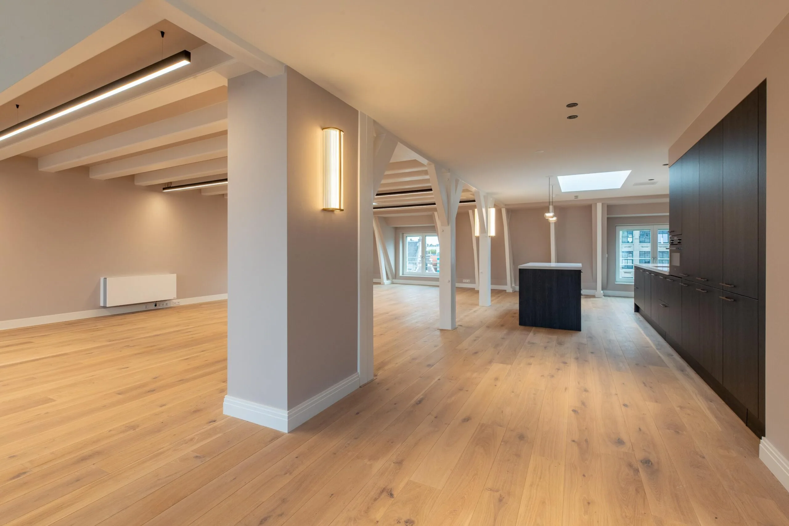 Modern open-plan apartment on Rokin with wooden flooring, exposed beams, and built-in dark cabinetry.