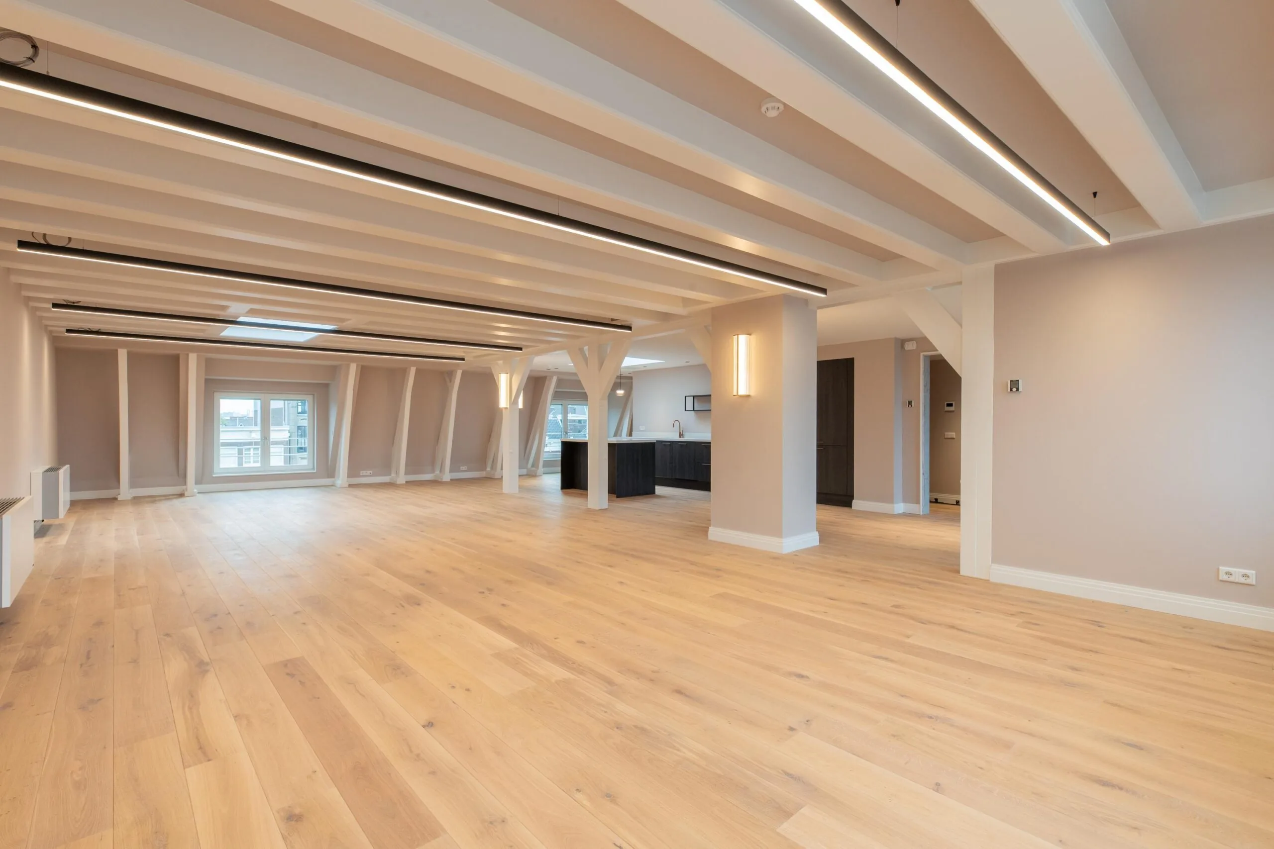 Spacious modern apartment on Rokin with light wooden floors, exposed beams, and large windows.