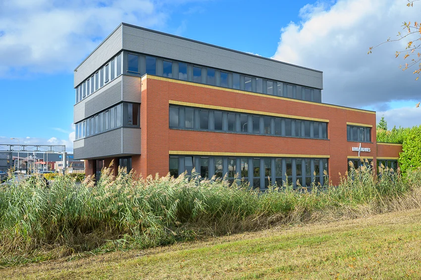 Modern office building of Ebweg in a grassy area under a blue sky with clouds.