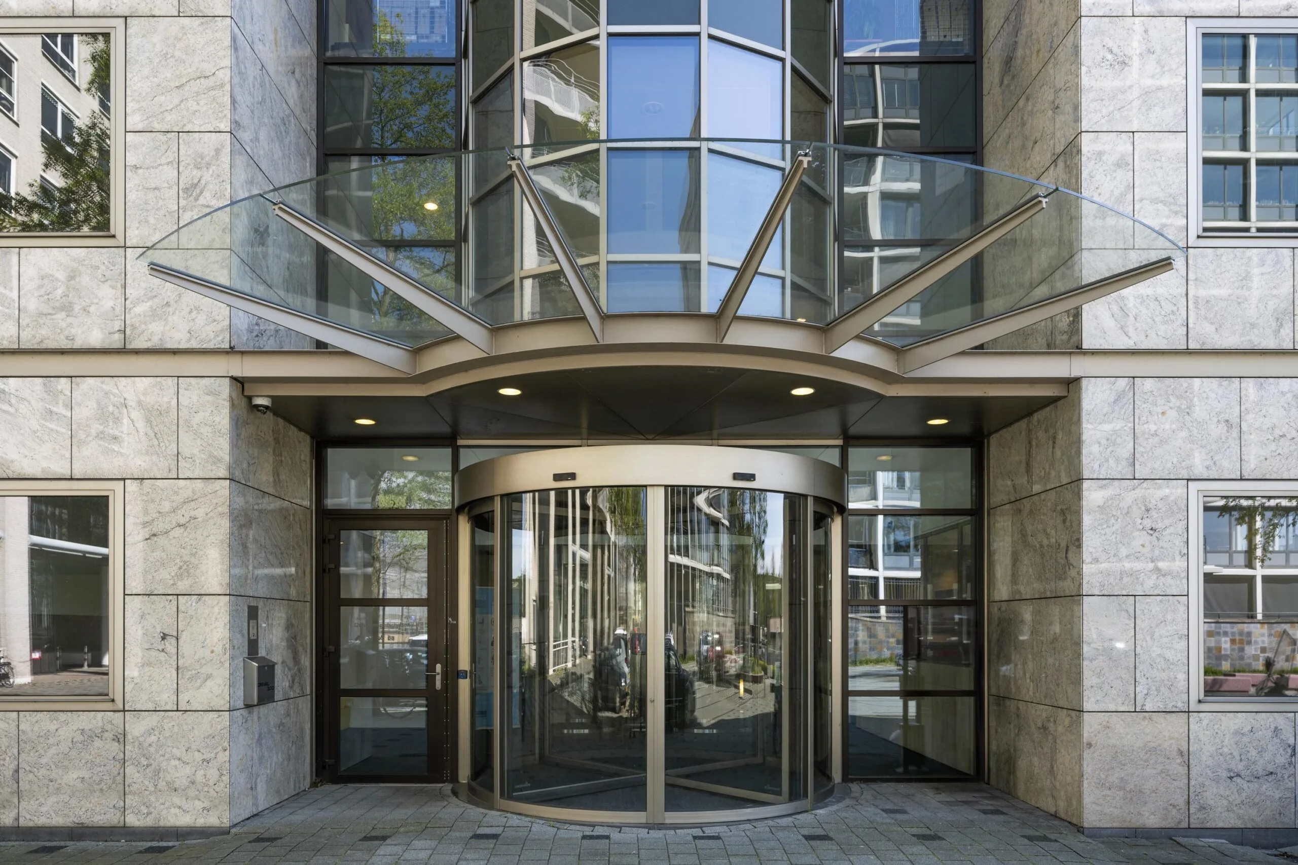 Main entrance of the Omval building with a glass revolving door and modern glass canopy.