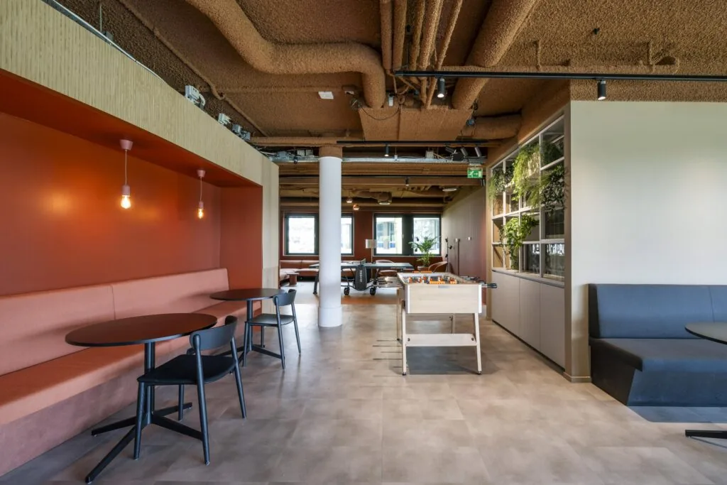 Modern office lounge at Omval with seating areas, a foosball table, and natural greenery.