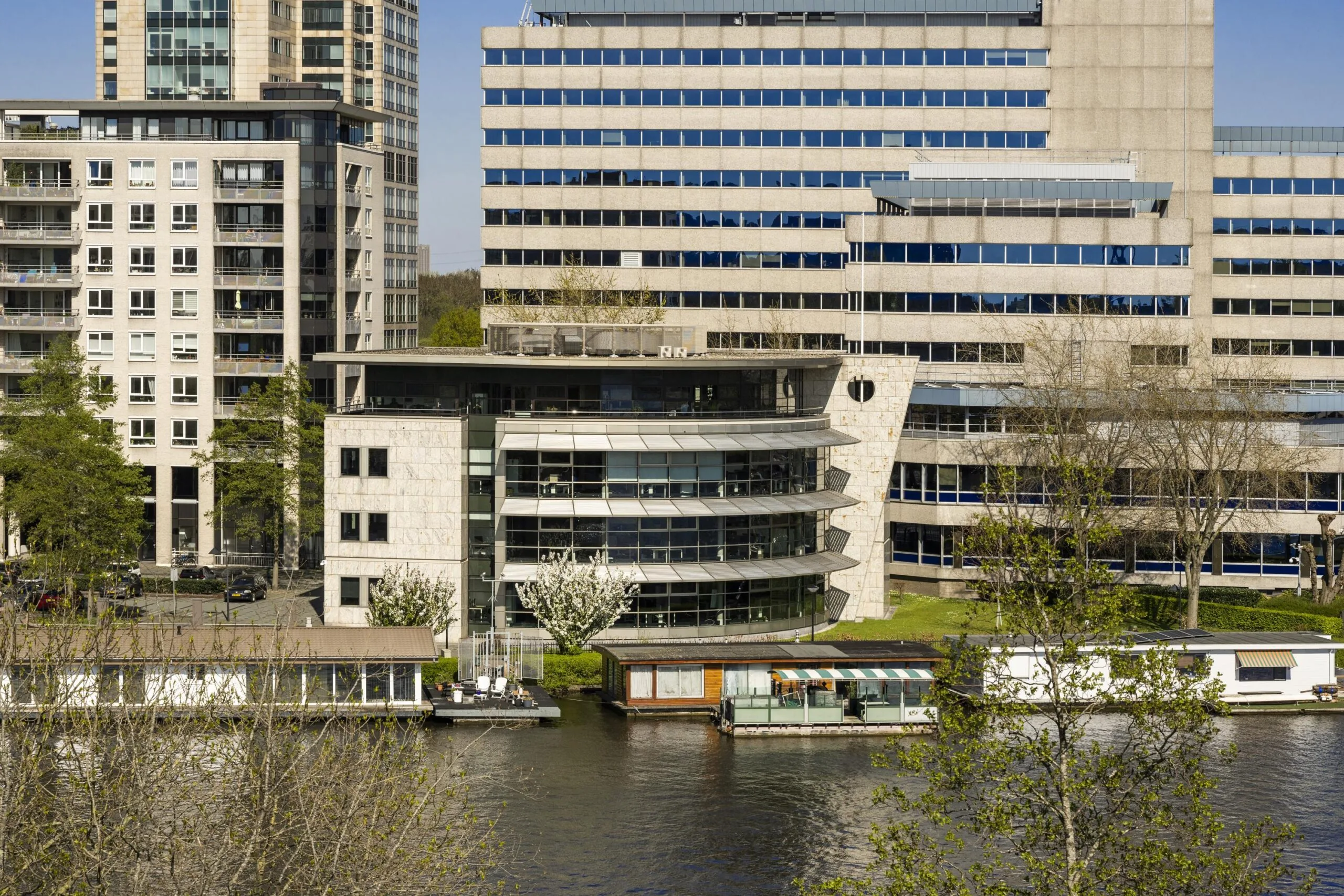 Modern office buildings and houseboats along the Omval waterfront in Amsterdam.
