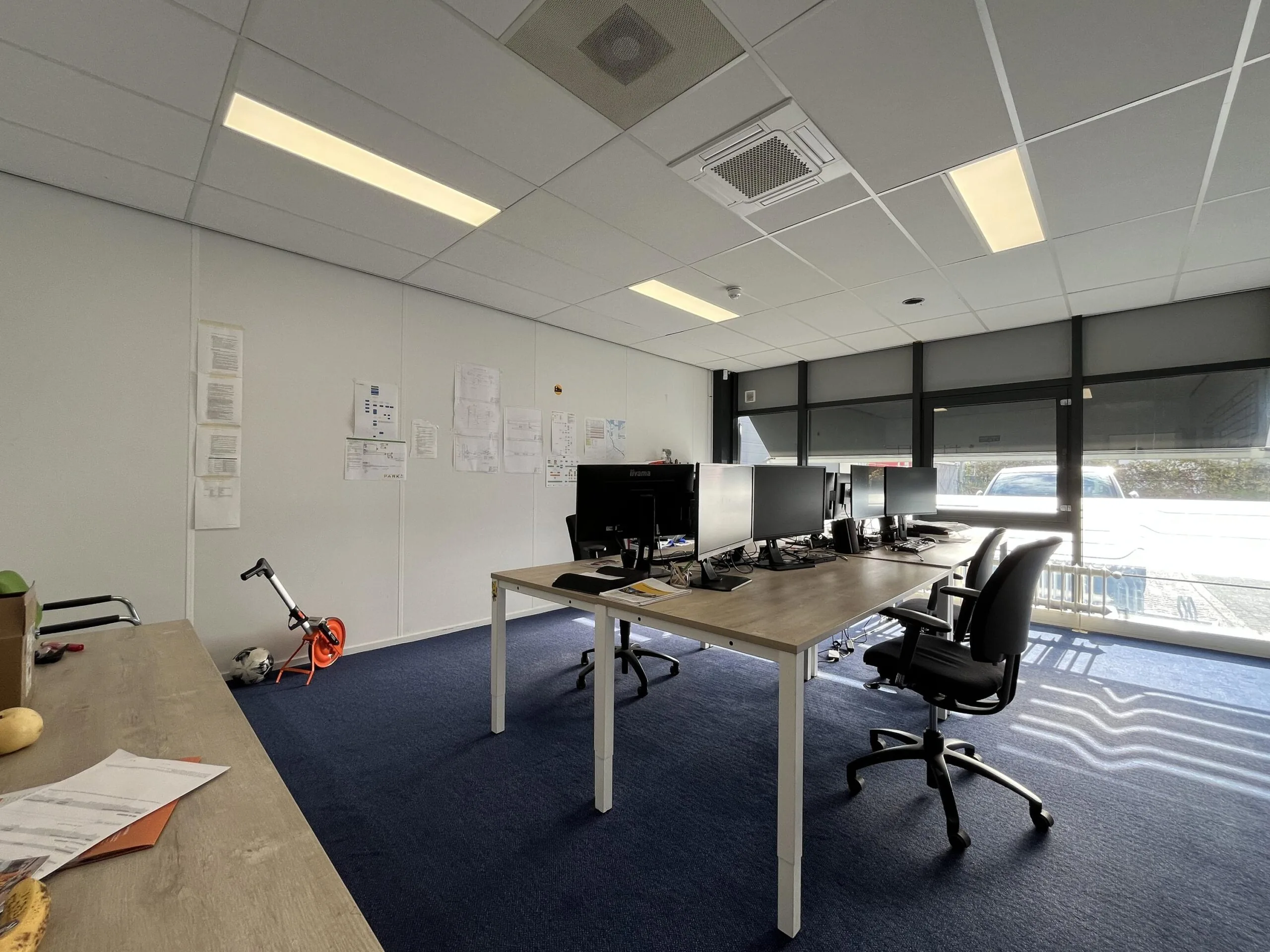 Modern office space on Archimedesbaan with desks, computer monitors, and a scooter near the wall.