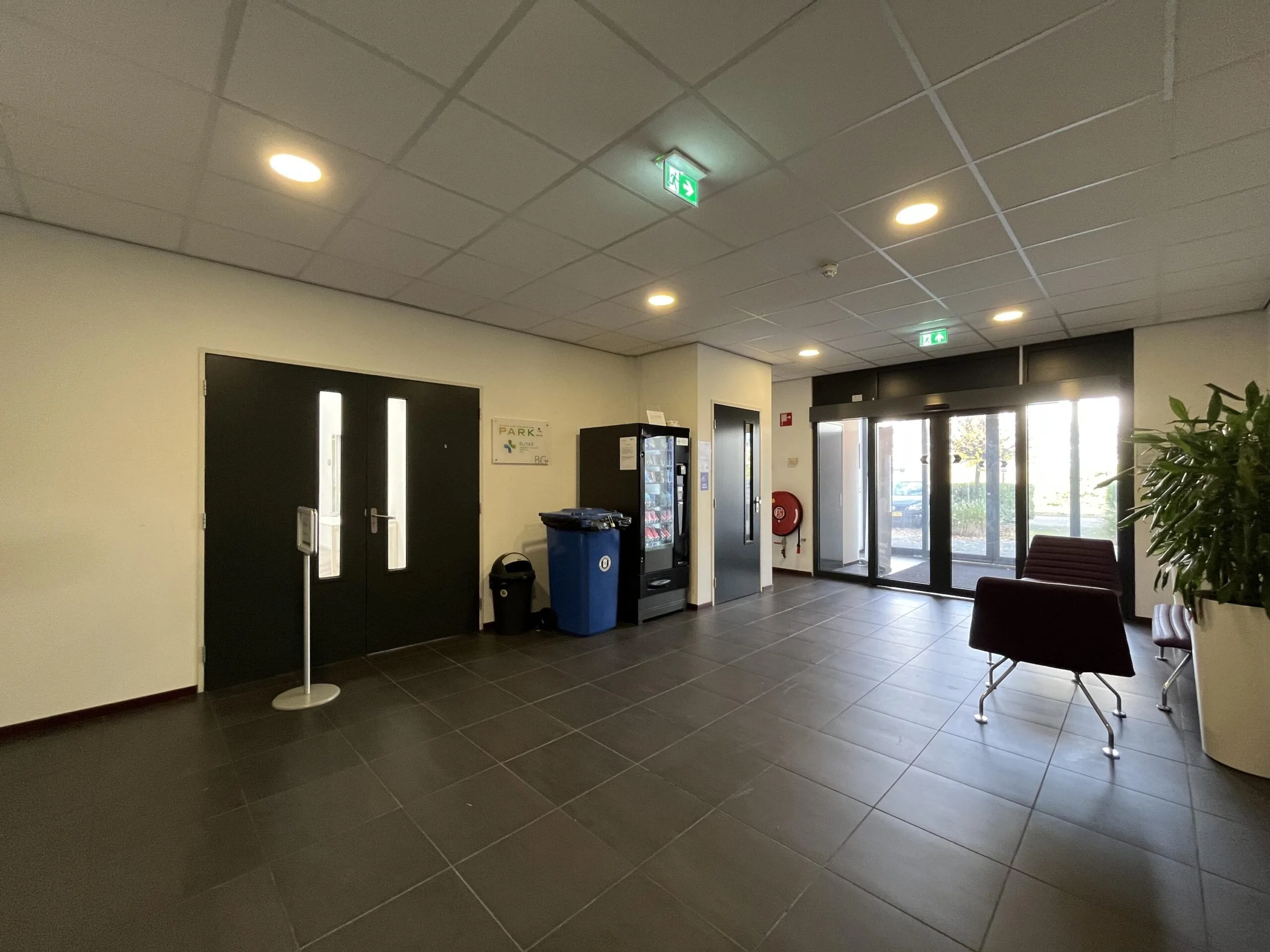 Modern entrance hall with vending machines, seating area, and glass doors at Archimedesbaan.