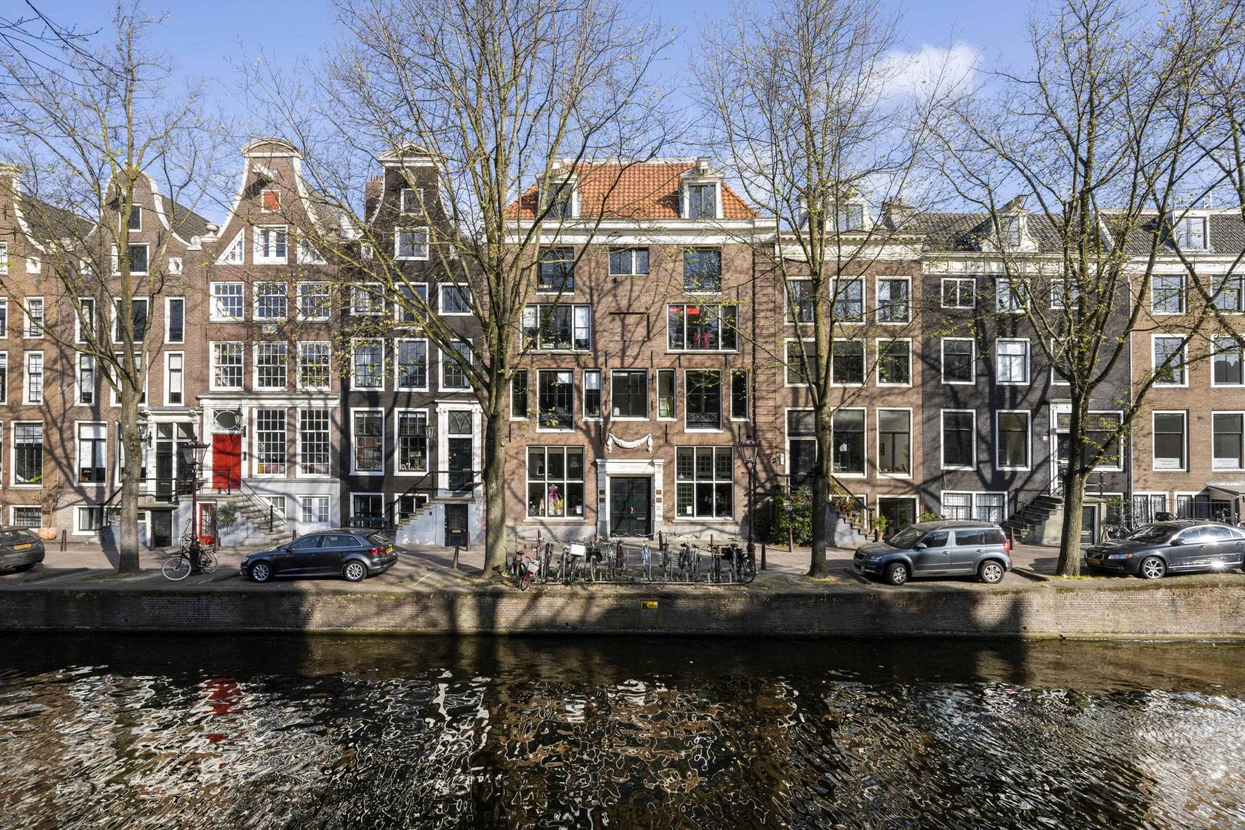 Historic canal houses along Leidsegracht in Amsterdam on a sunny day with reflections in the water.