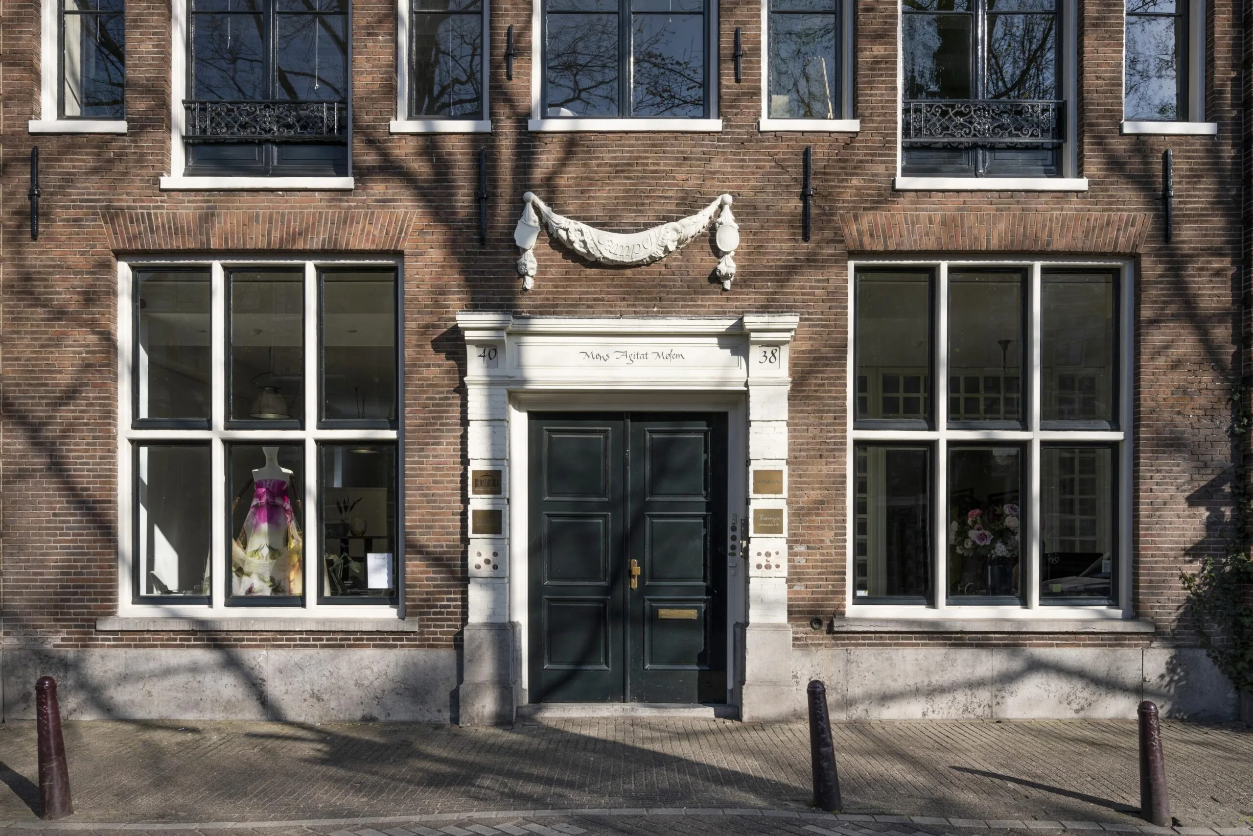 Historic canal house facade on Leidsegracht in Amsterdam with large windows, a central dark green door, and decorative white stone detailing.