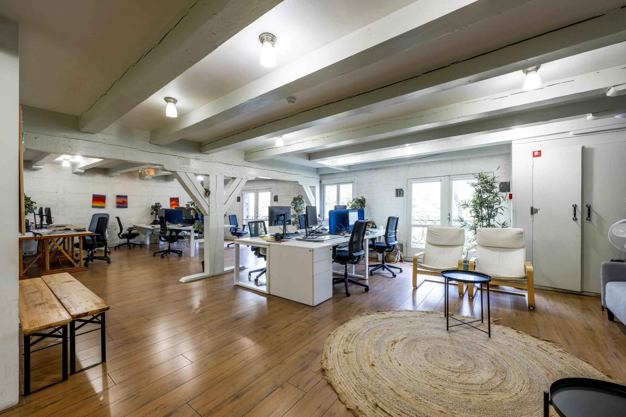 Modern open-plan office space on Leidsegracht with wooden floors, white beams, and ergonomic workstations.