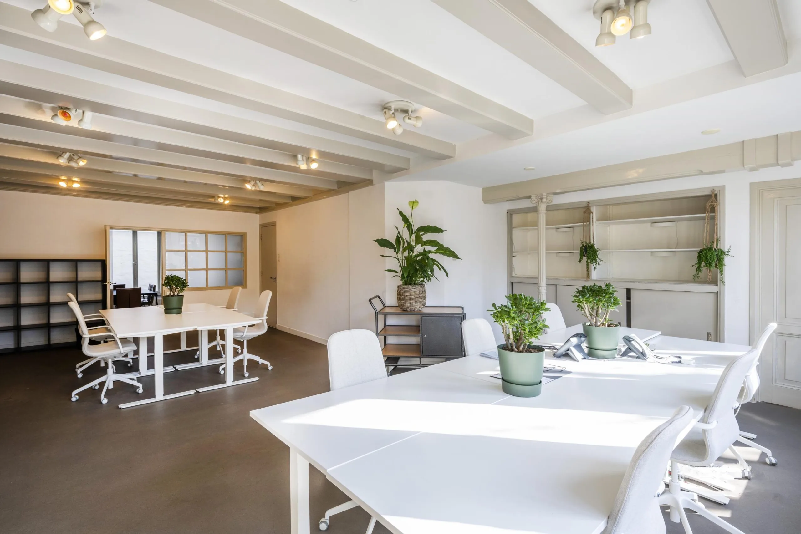 Bright and modern office space on Leidsegracht with white desks, ergonomic chairs, and green potted plants.