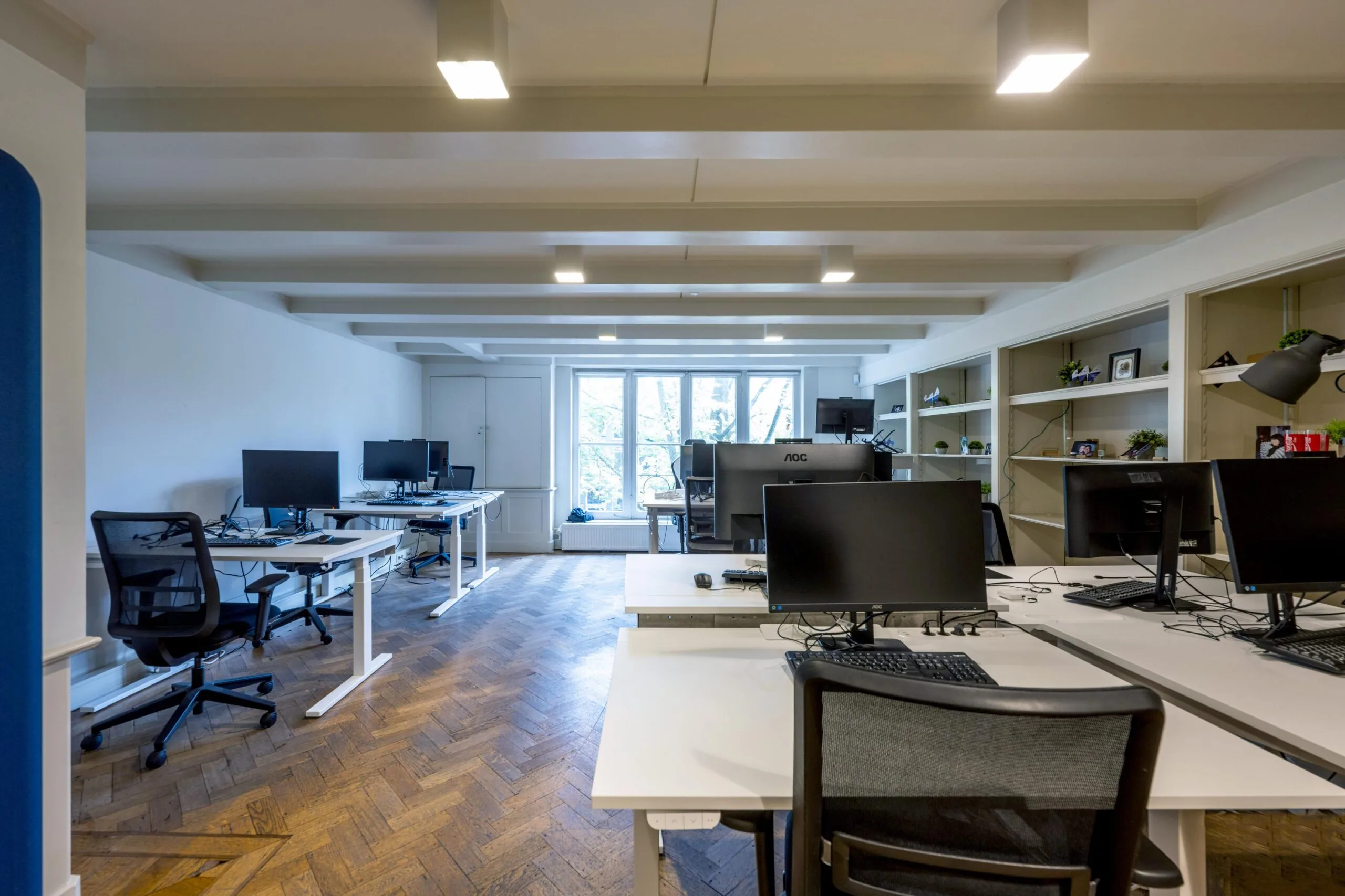 Modern open-plan office space on Leidsegracht with multiple desks, computer monitors, and large windows providing natural light.