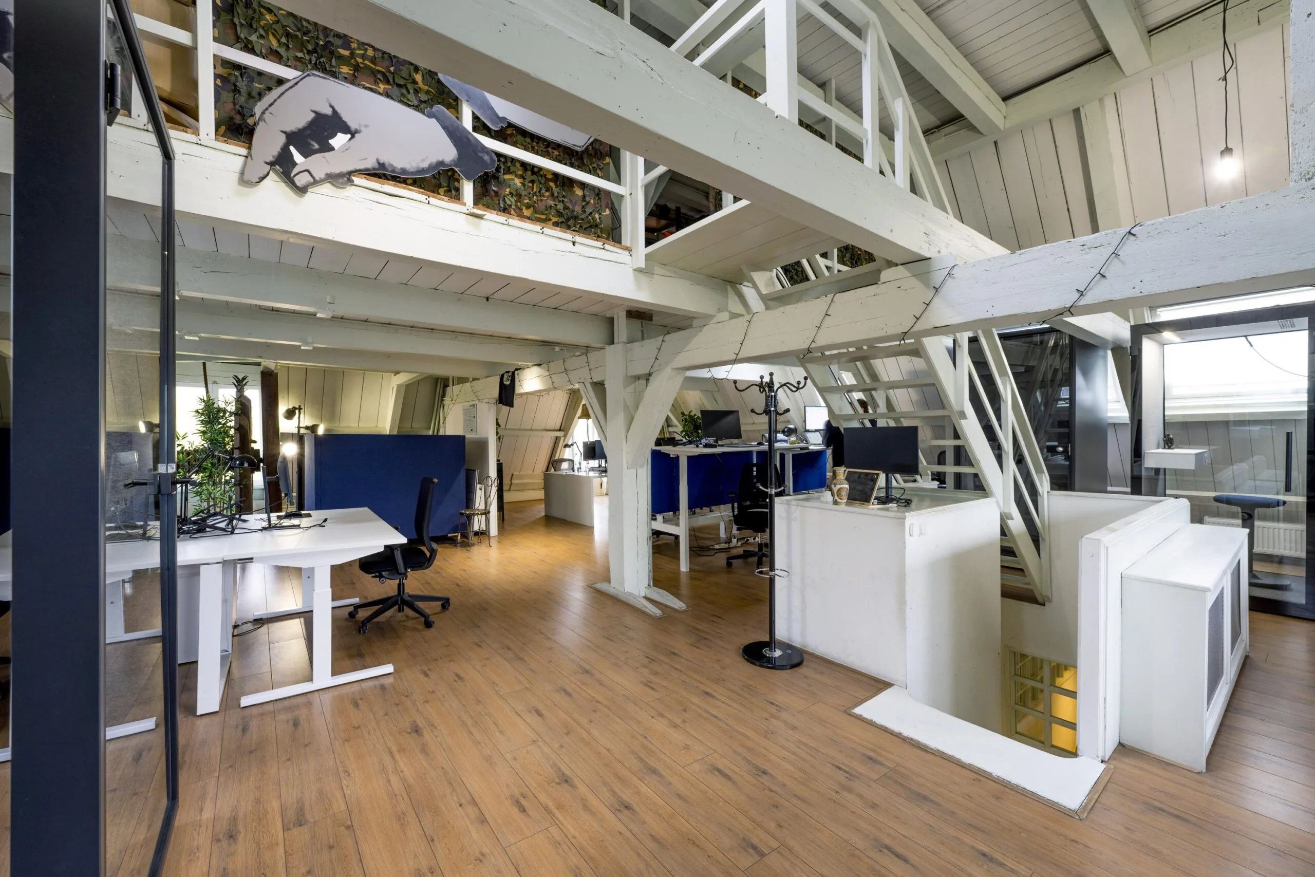 Modern loft-style office space on Leidsegracht with wooden floors, white beams, and multiple workstations.