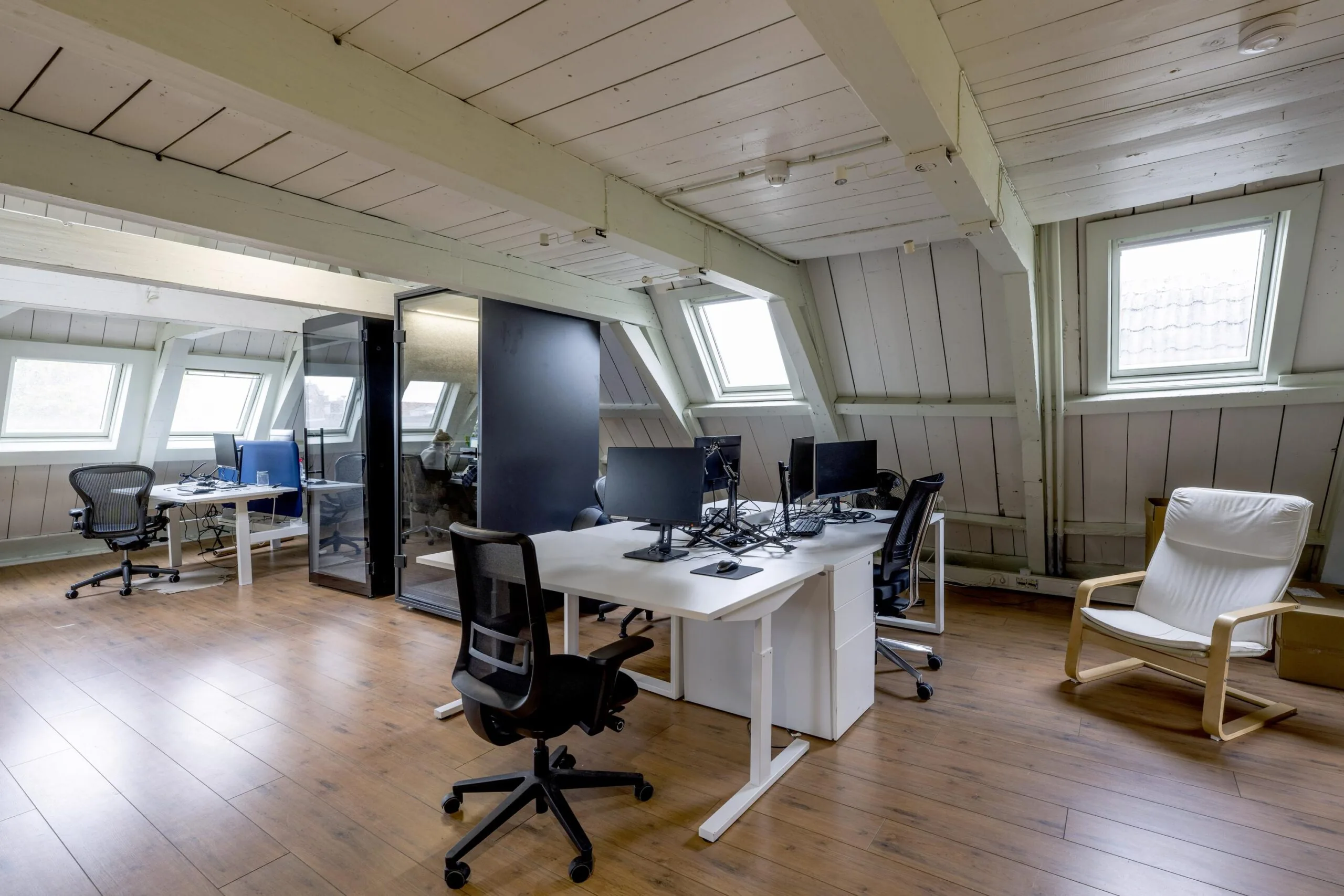 Modern attic office space on Leidsegracht with wooden floors, desks, office chairs, and skylight windows.