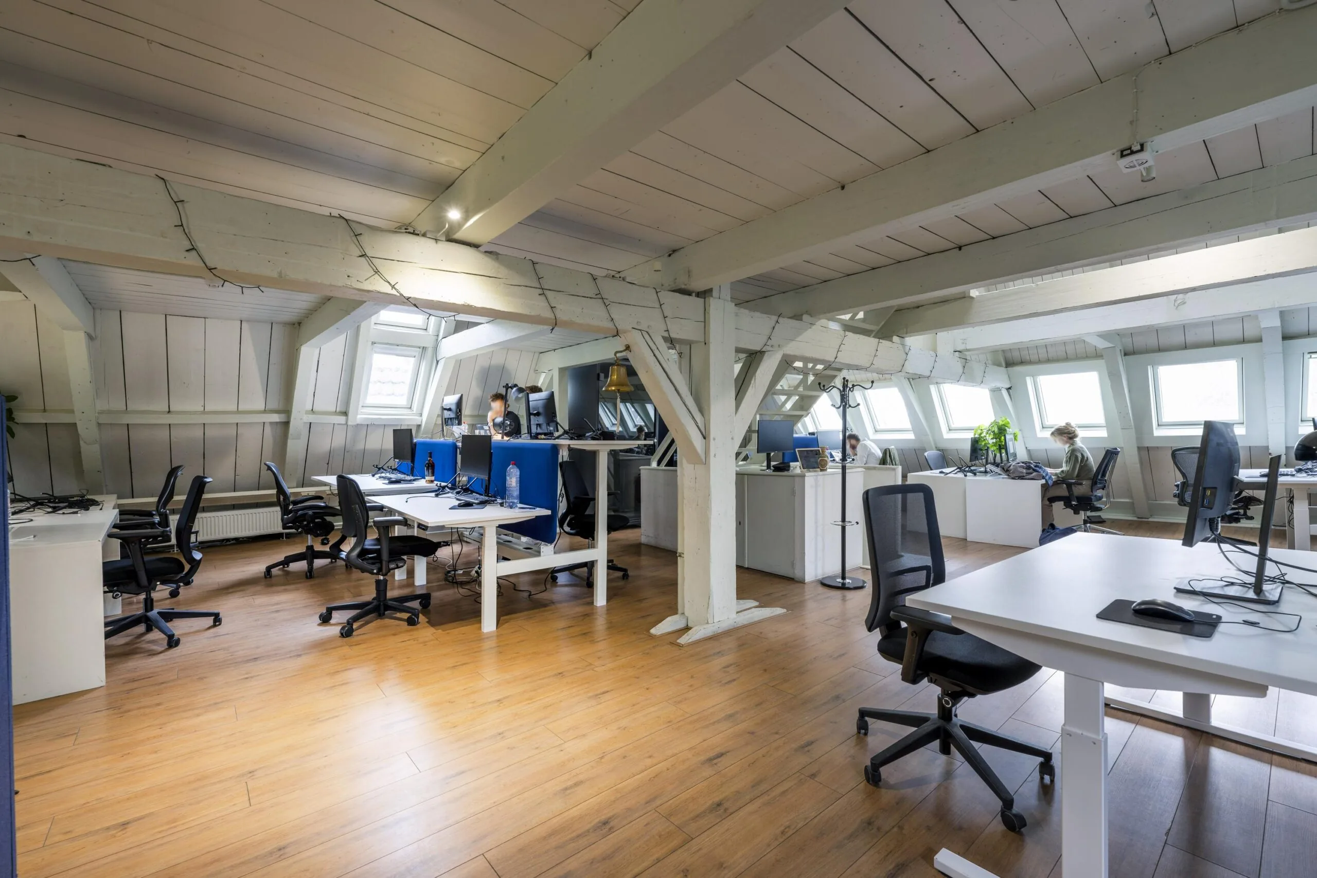 Modern attic office space on Leidsegracht with wooden floors, exposed beams, and multiple workstations.