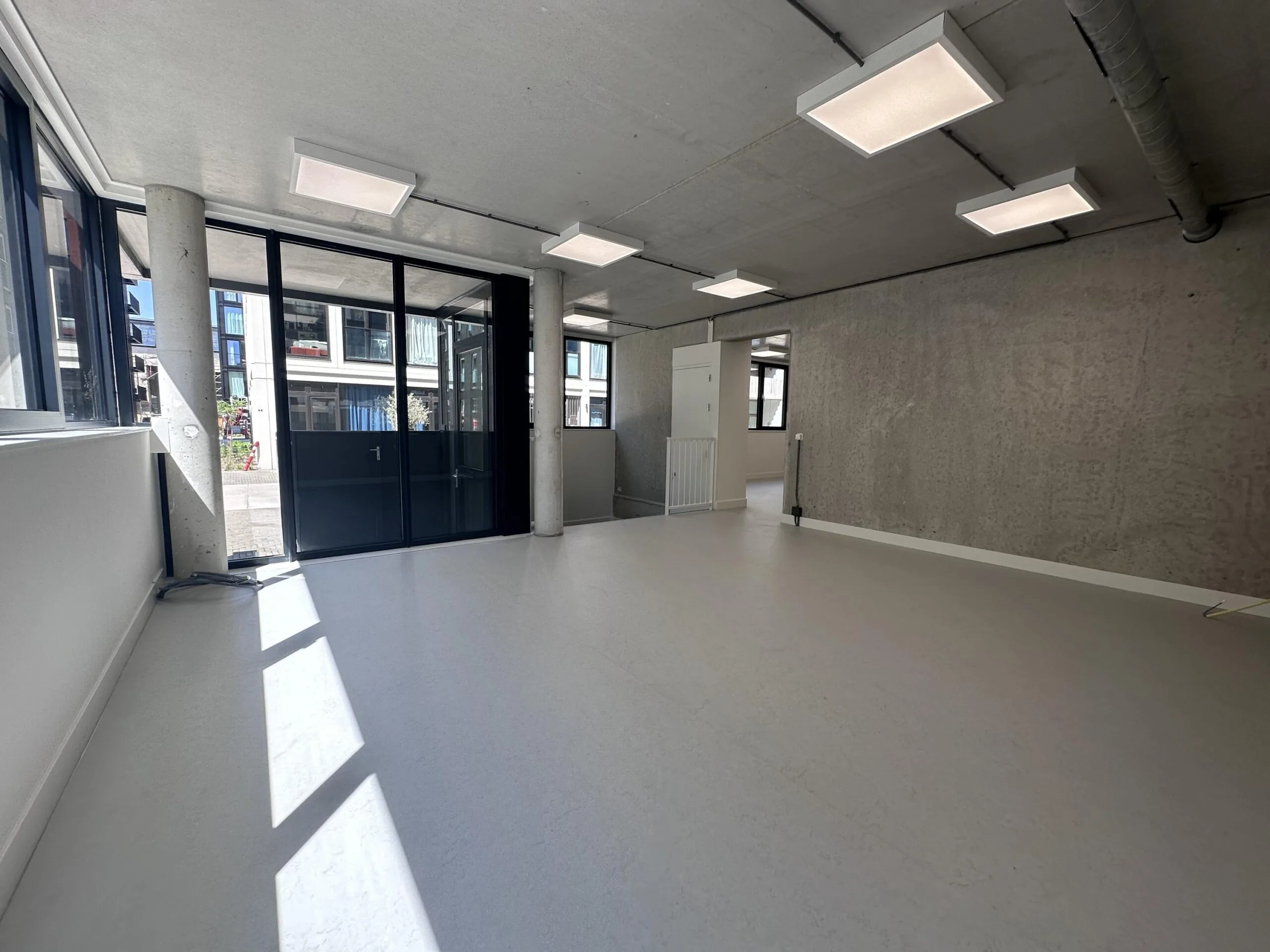 Bright, unfurnished commercial space on Willem Parelstraat with large windows and concrete walls.