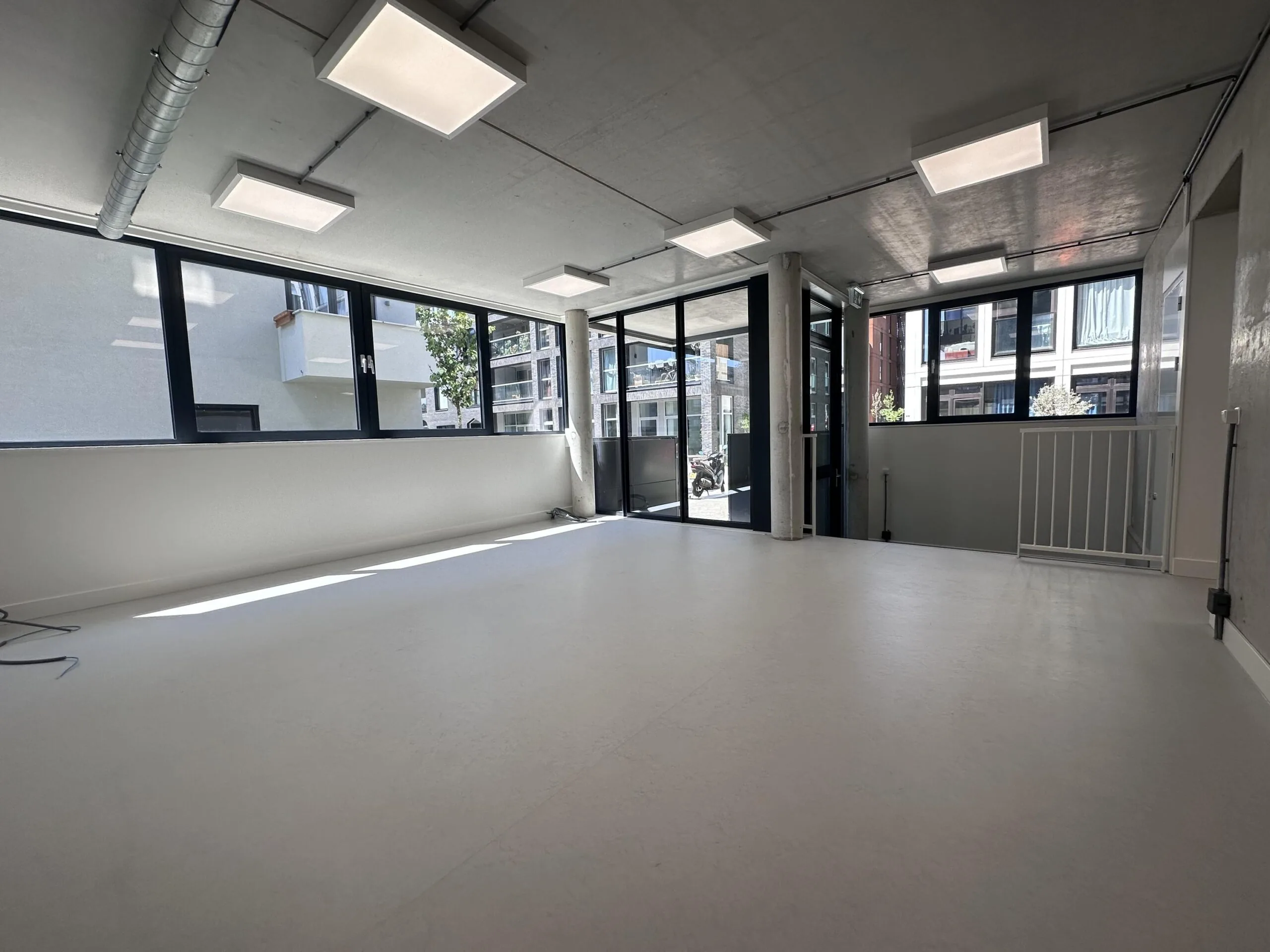 Bright, empty commercial space on Willem Parelstraat with large windows and modern ceiling lights.