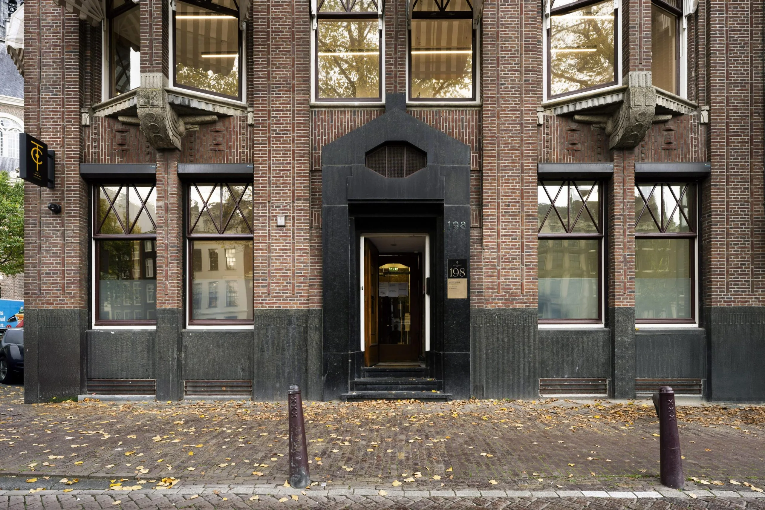 Entrance of a historic brick building at Westermarkt 198 in Amsterdam with large windows and Art Deco architectural details.