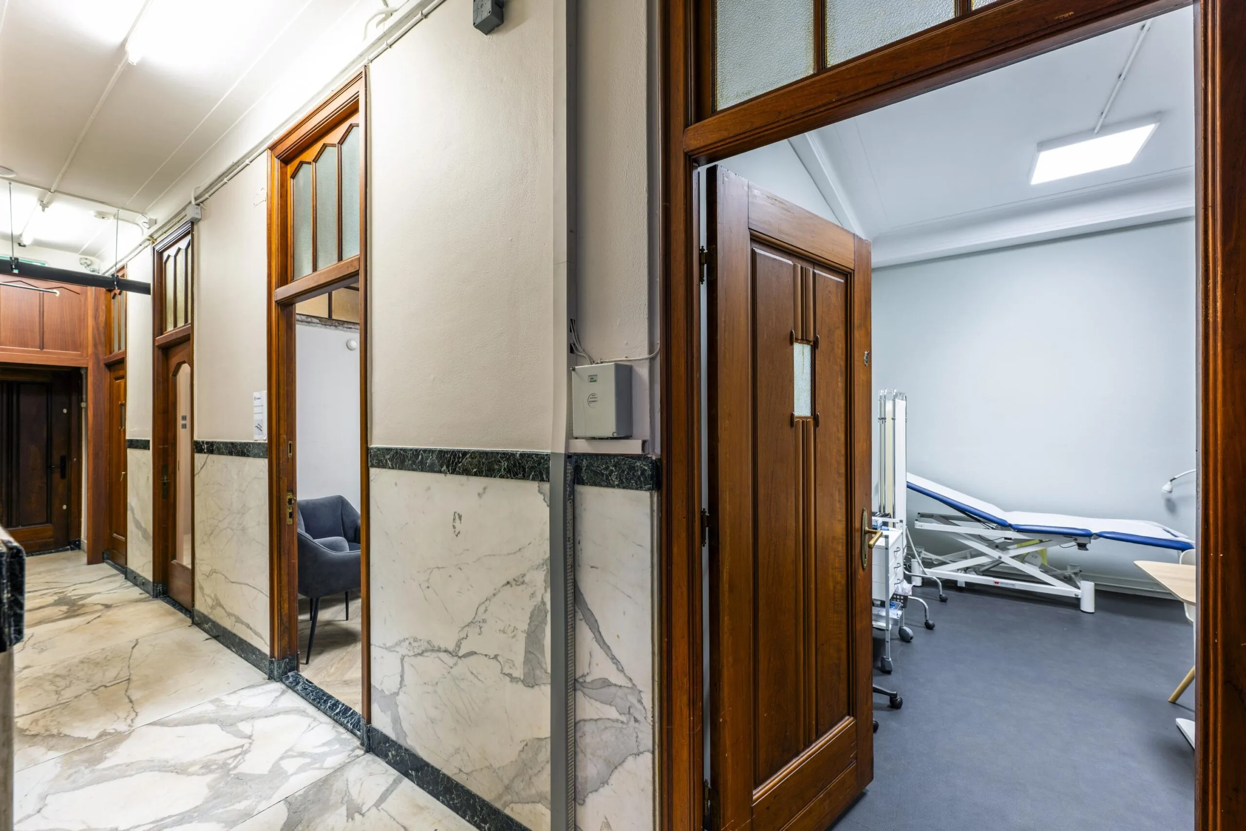 Medical examination room visible through an open wooden door in a hallway at Westermarkt.