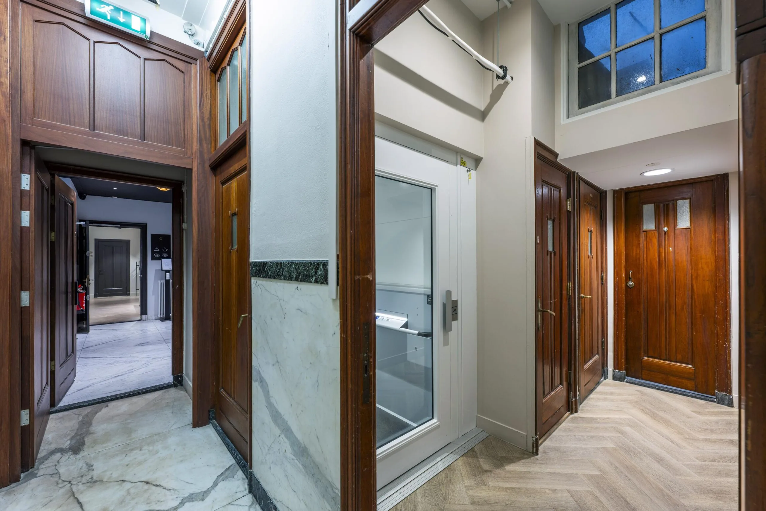 Interior hallway of the Westermarkt building featuring wooden doors, a modern elevator, and marble flooring.