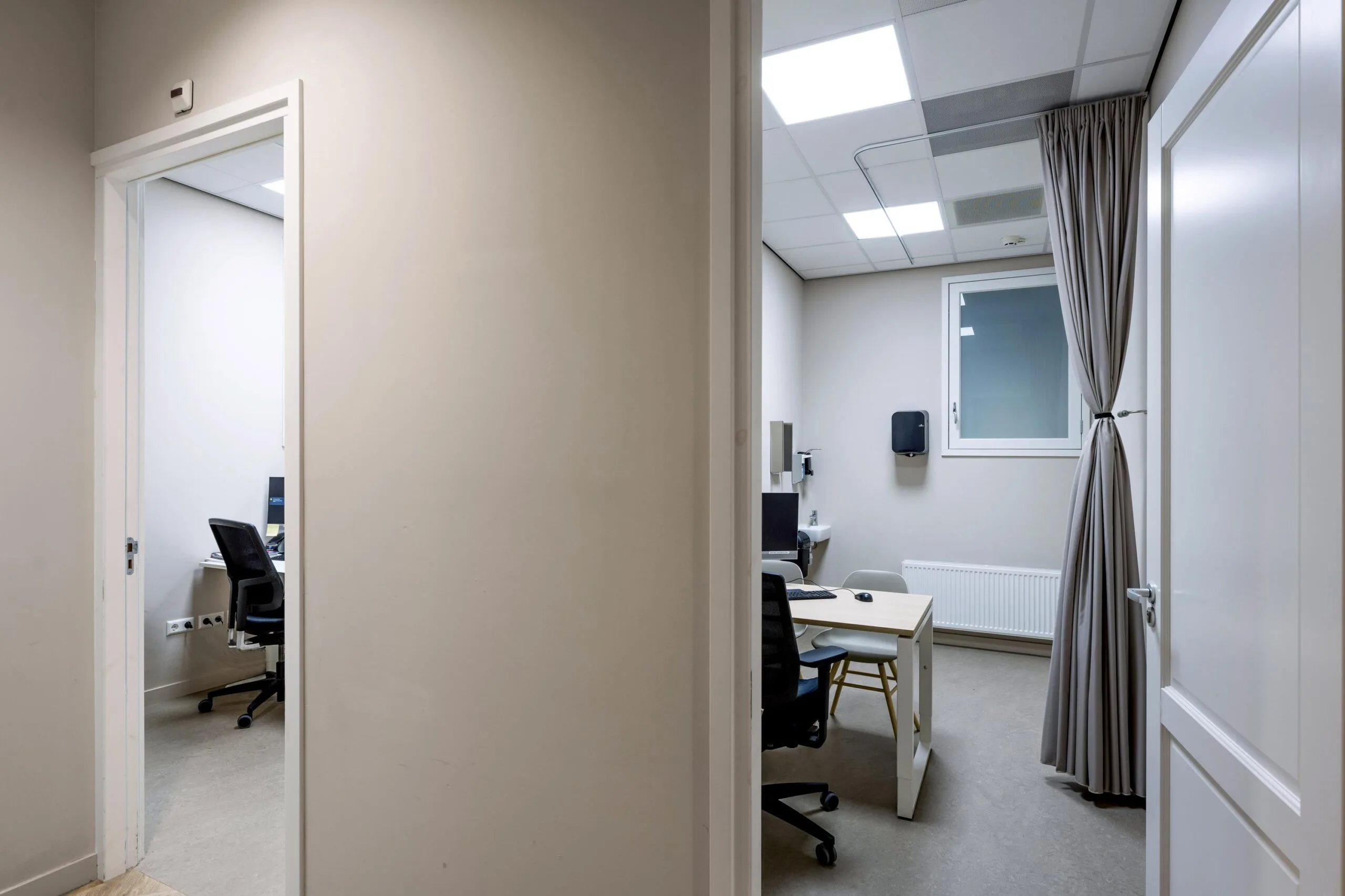 Two small medical consultation rooms at Westermarkt, each equipped with a desk, chairs, and a computer.
