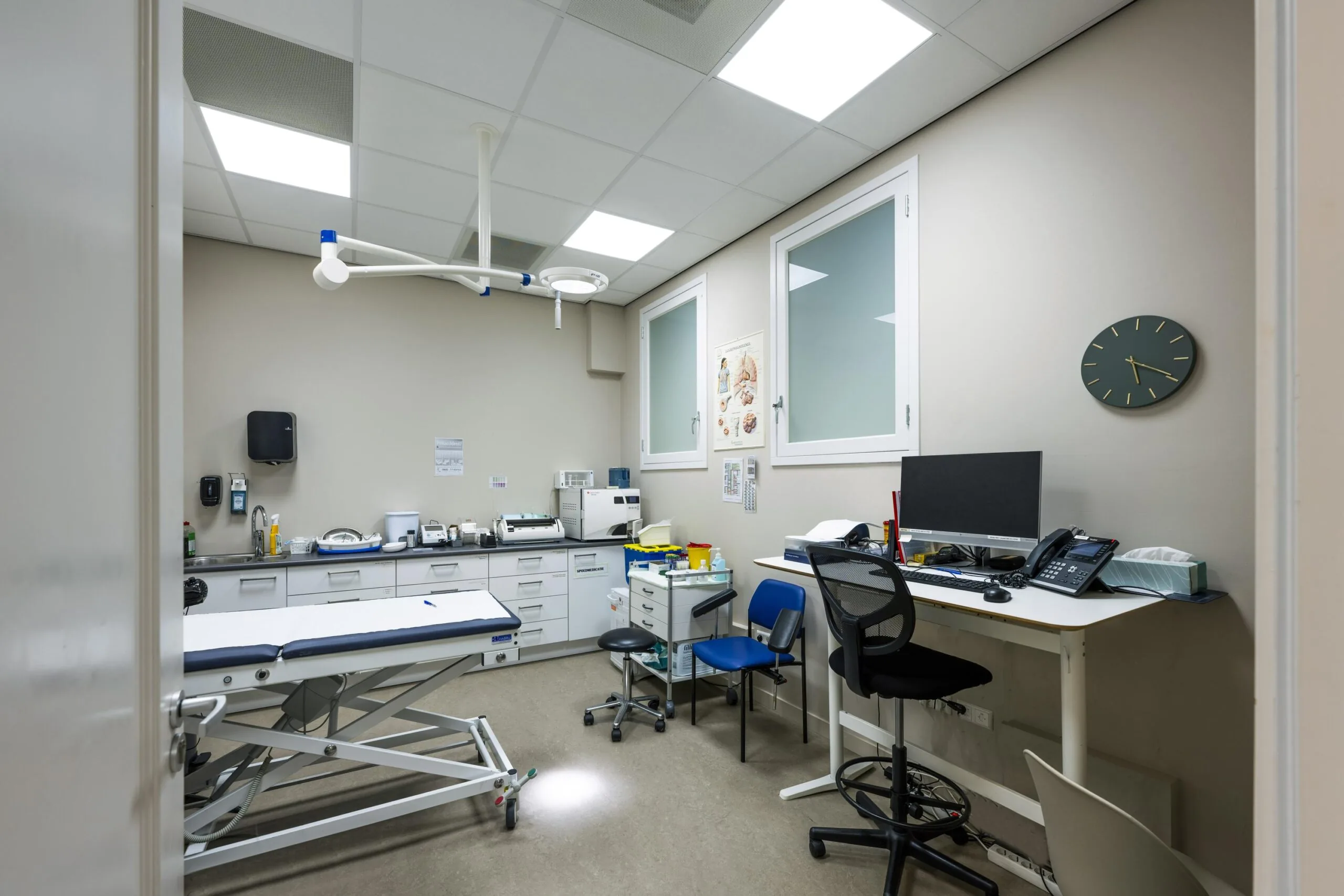 Modern medical examination room at Westermarkt with a treatment table, diagnostic equipment, and a computer workstation.