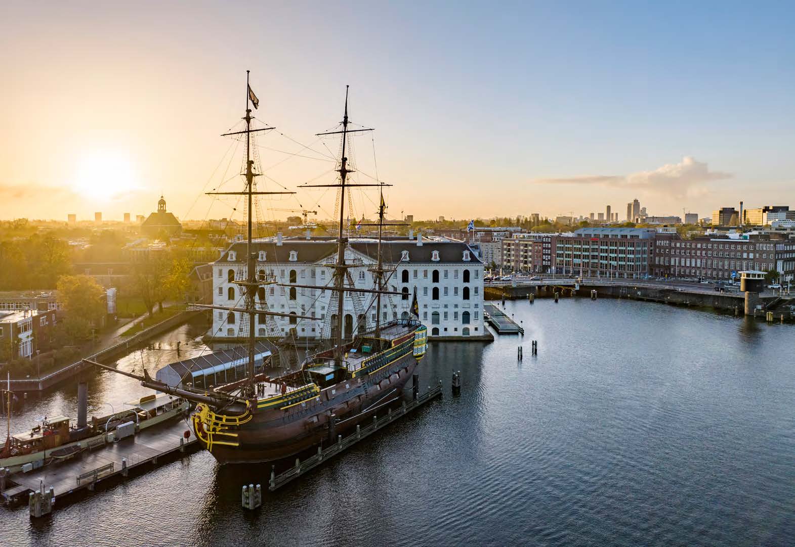 Historic ship moored at the Maritime Museum on the Nieuwe Vaart canal in Amsterdam at sunset.