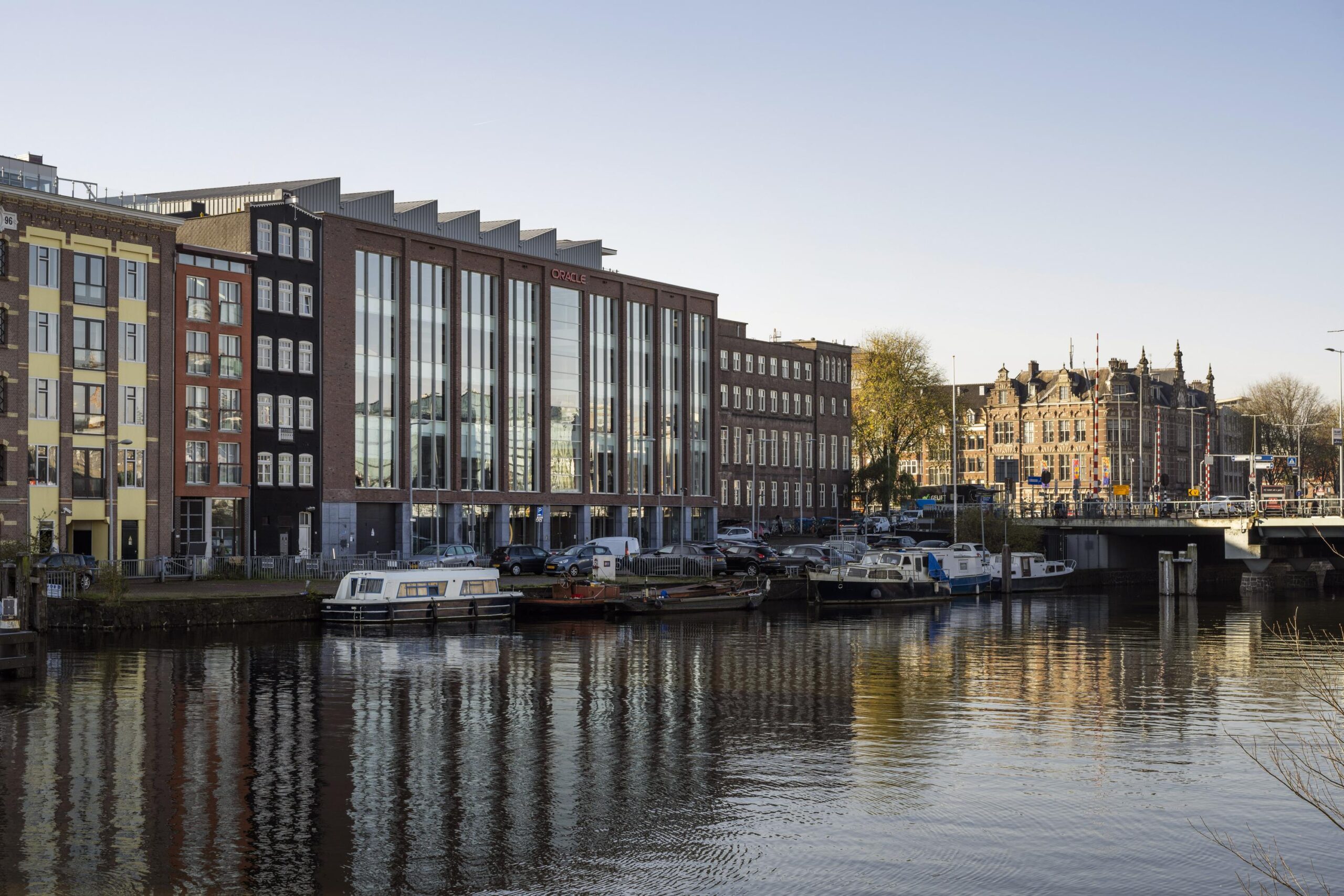 Modern office buildings and moored boats along the Nieuwe Vaart canal in Amsterdam.