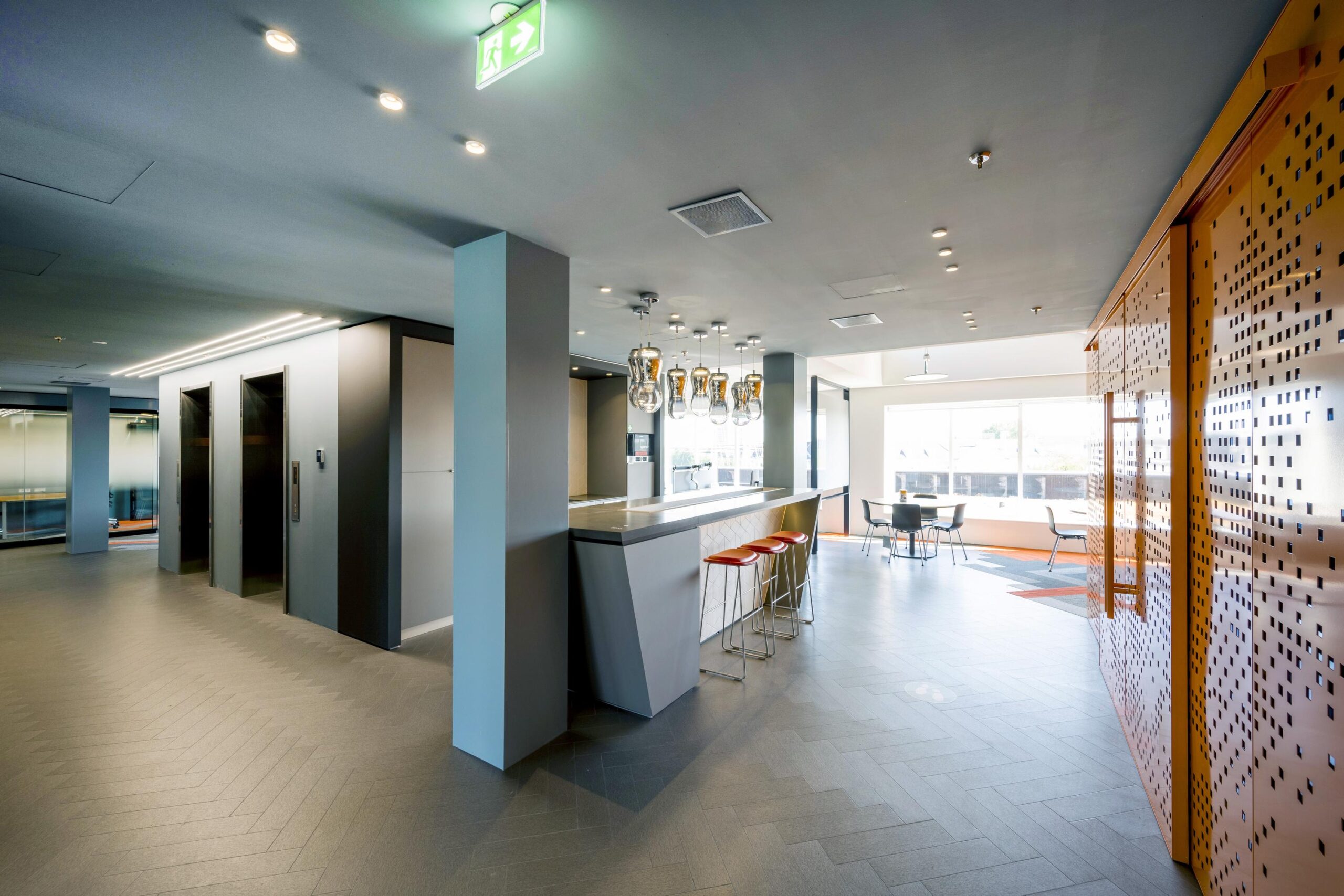 Modern office interior at Nieuwe Vaart with a sleek bar, elevators, and lounge seating area.