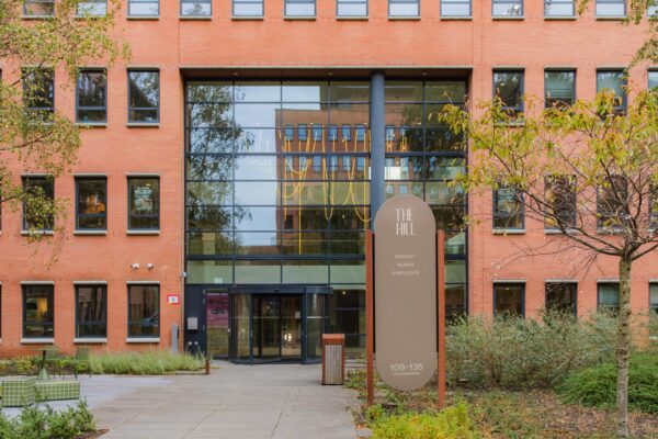 Front view of the office building "The Hill" at Hullenbergweg 109–135 with a sign listing companies including Basenet, Blinxx, and Simplicate.