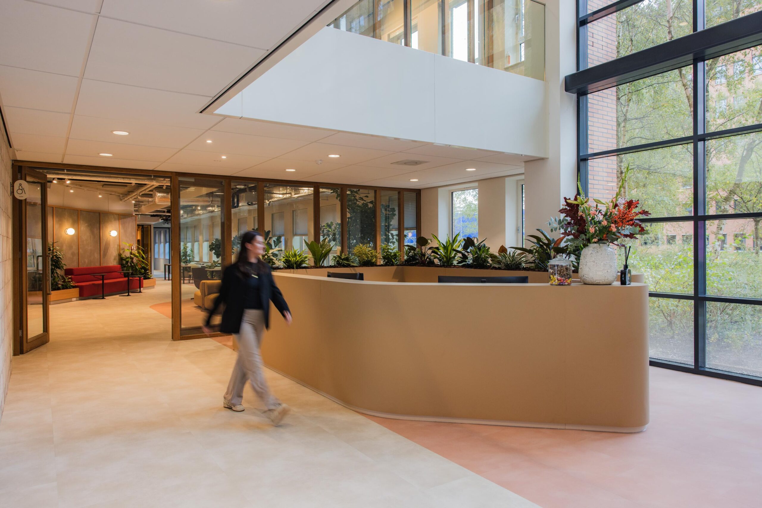 Modern reception area at Hullenbergweg with natural light, indoor plants, and a curved desk.