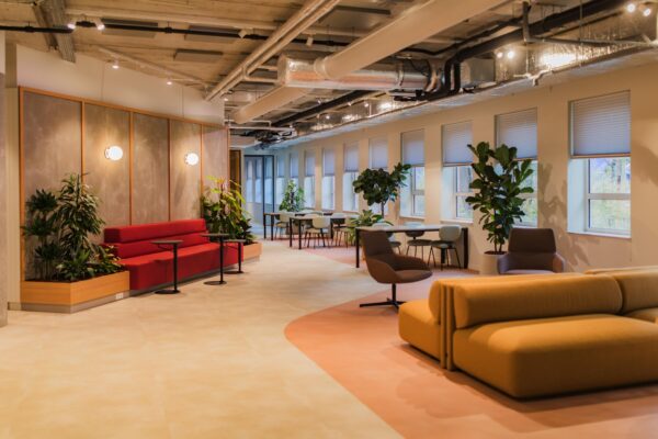 Modern office lounge on Hullenbergweg with colorful seating, indoor plants, and large windows.