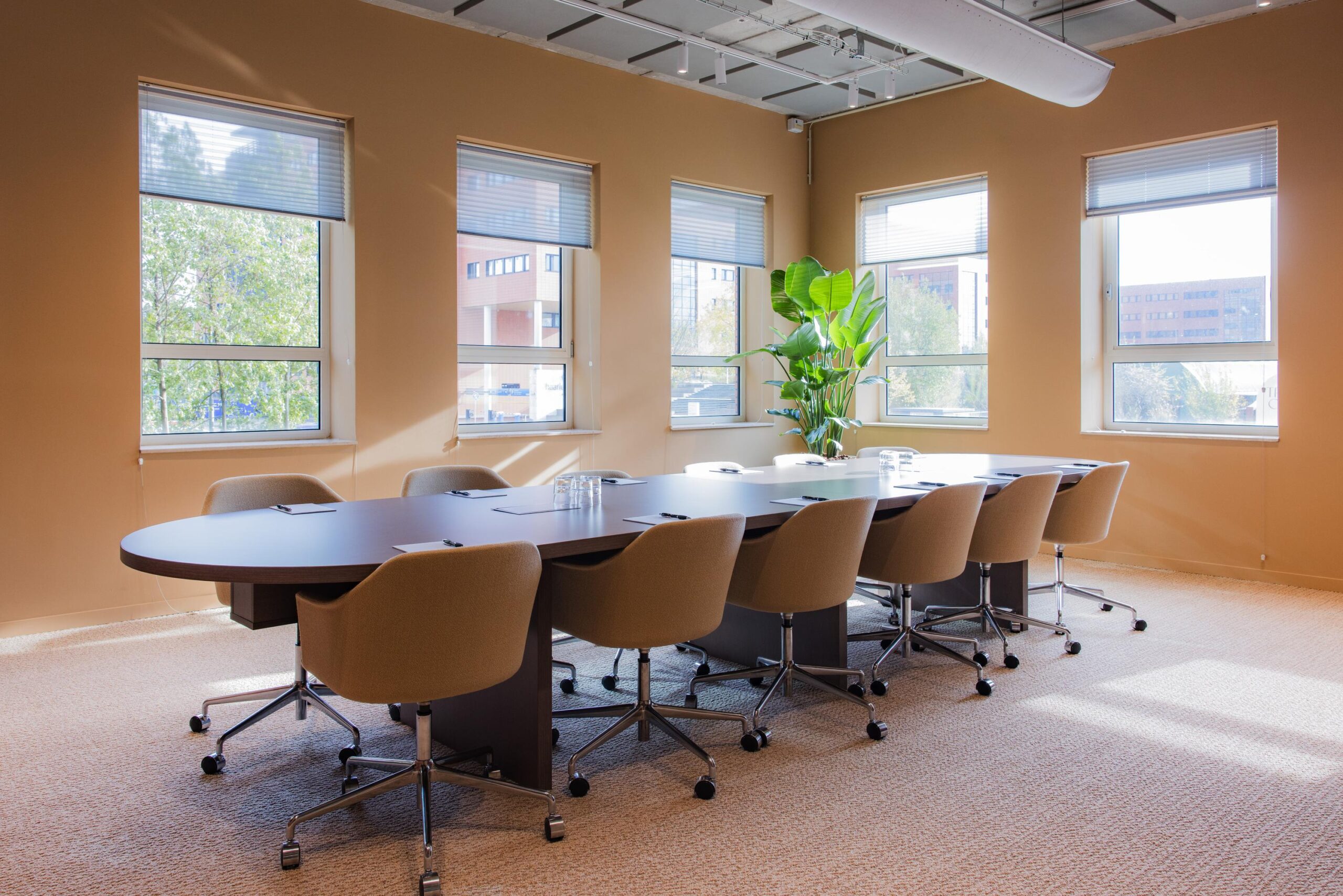 Modern conference room on Hullenbergweg with a large oval table, office chairs, and natural light from multiple windows.