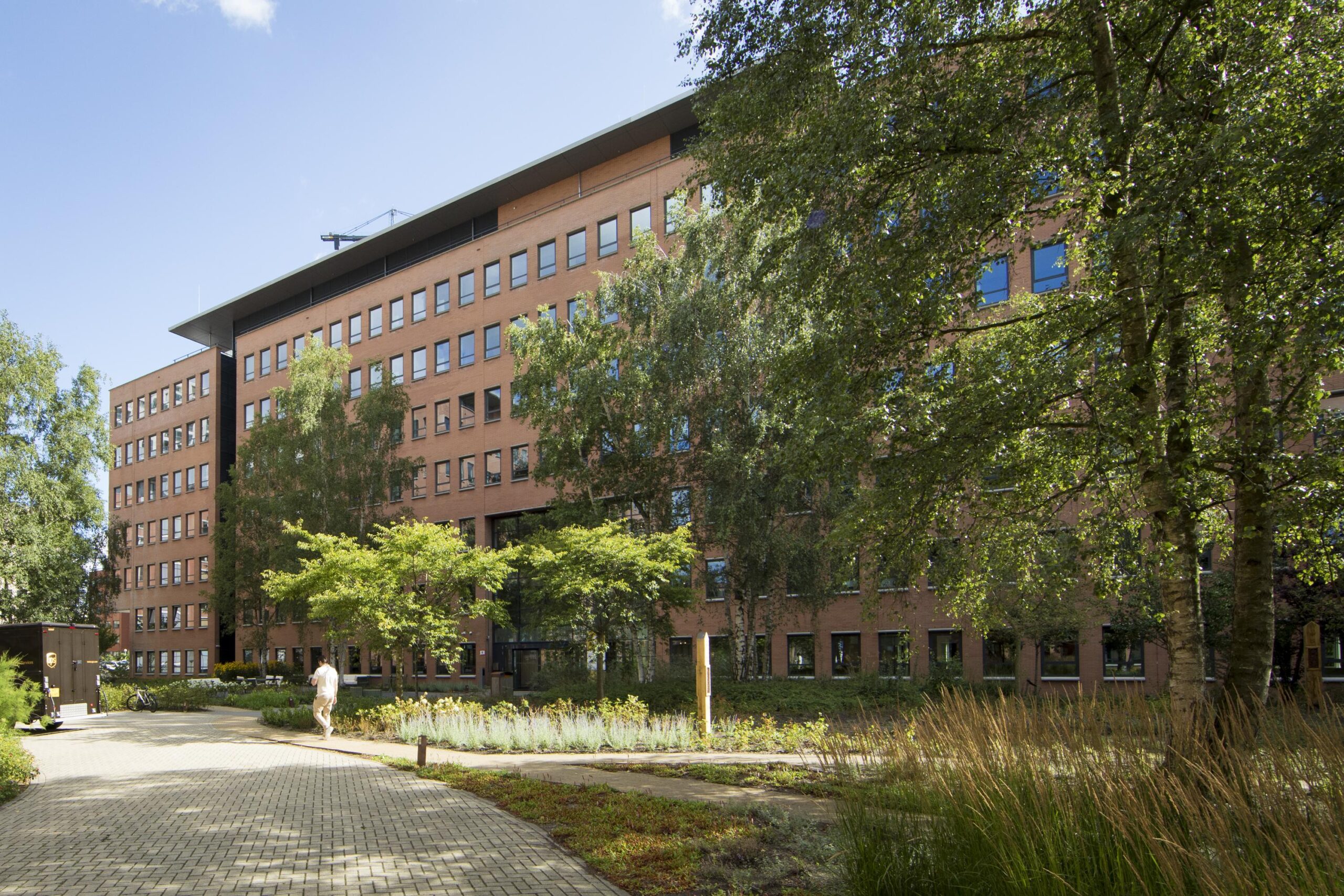 Modern office building on Hullenbergweg surrounded by trees and greenery on a sunny day.
