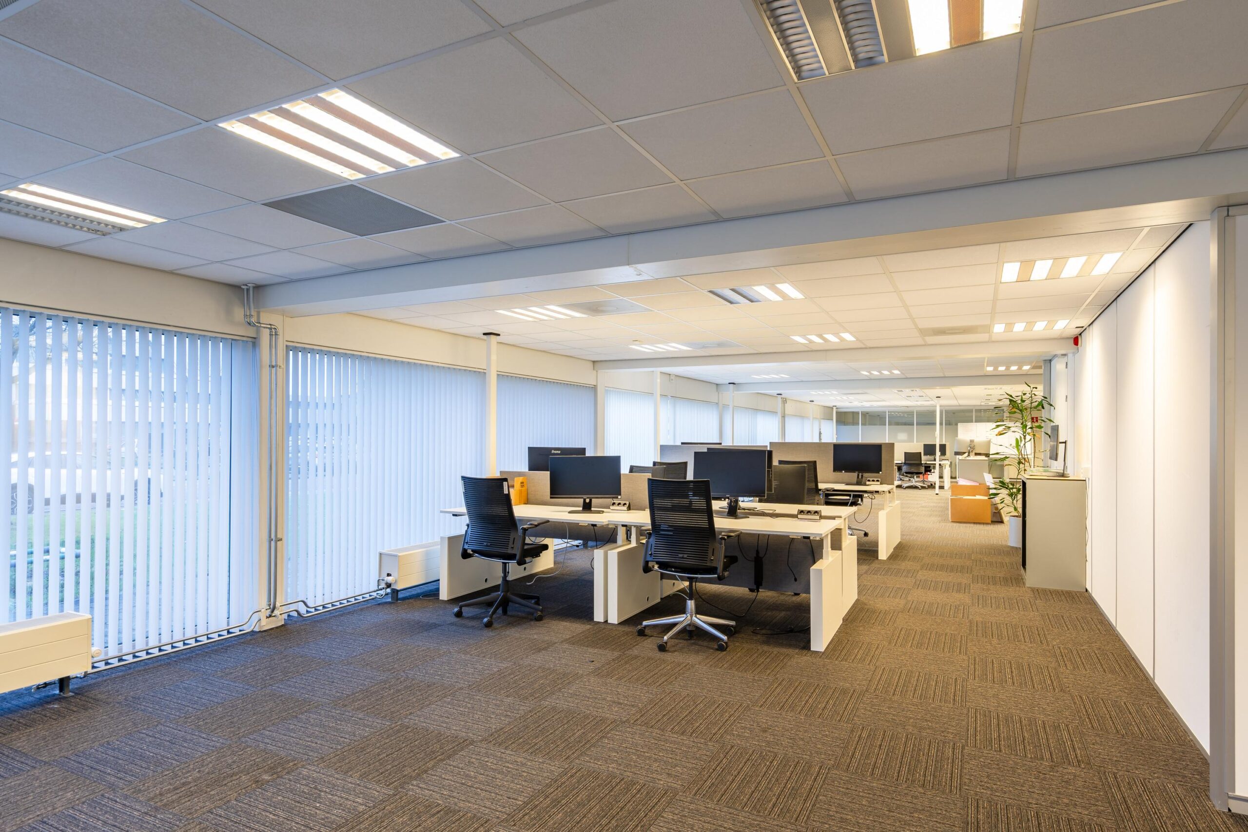 Een moderne, open kantoorruimte aan de Gravelandseweg met bureaus, computerschermen en ergonomische stoelen.