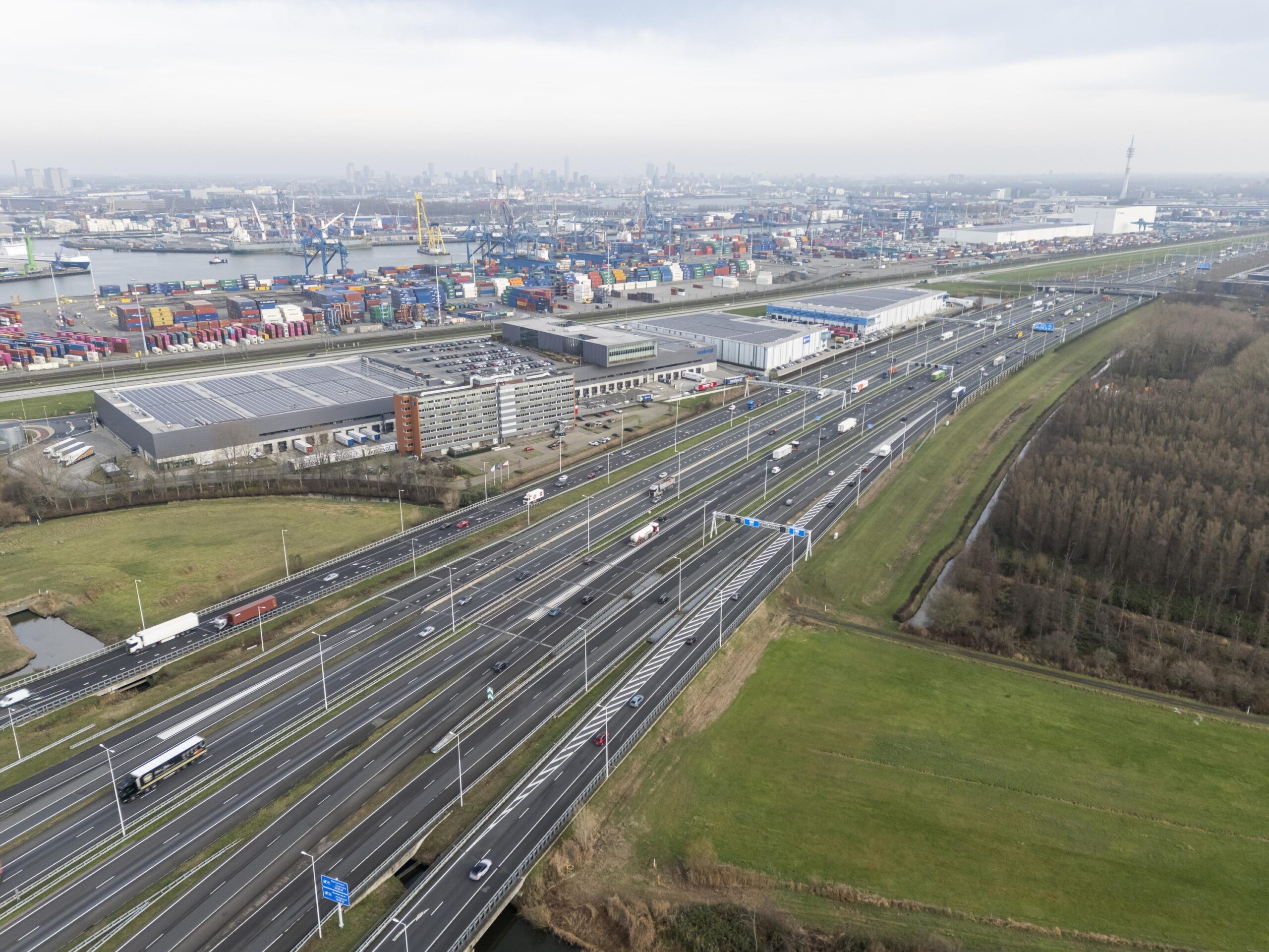 Luchtfoto van de Seattleweg in Rotterdam met naastgelegen snelweg, haventerrein en containeroverslag.