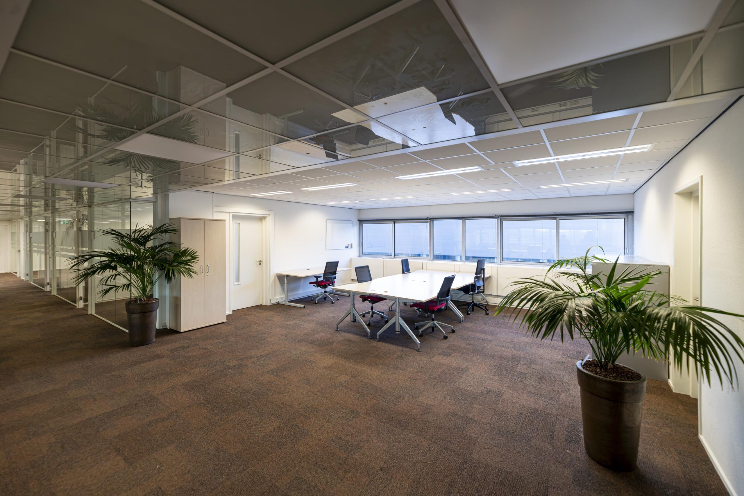 Moderne kantoorruimte aan de Seattleweg met vergadertafel, bureaus, bureaustoelen en grote raampartijen.