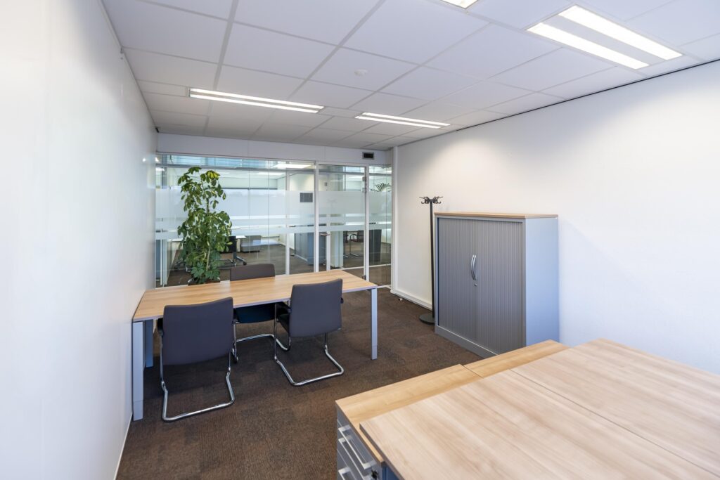 Moderne kantoorruimte aan de Seattleweg met bureaus, stoelen, een opbergkast en een glazen scheidingswand.