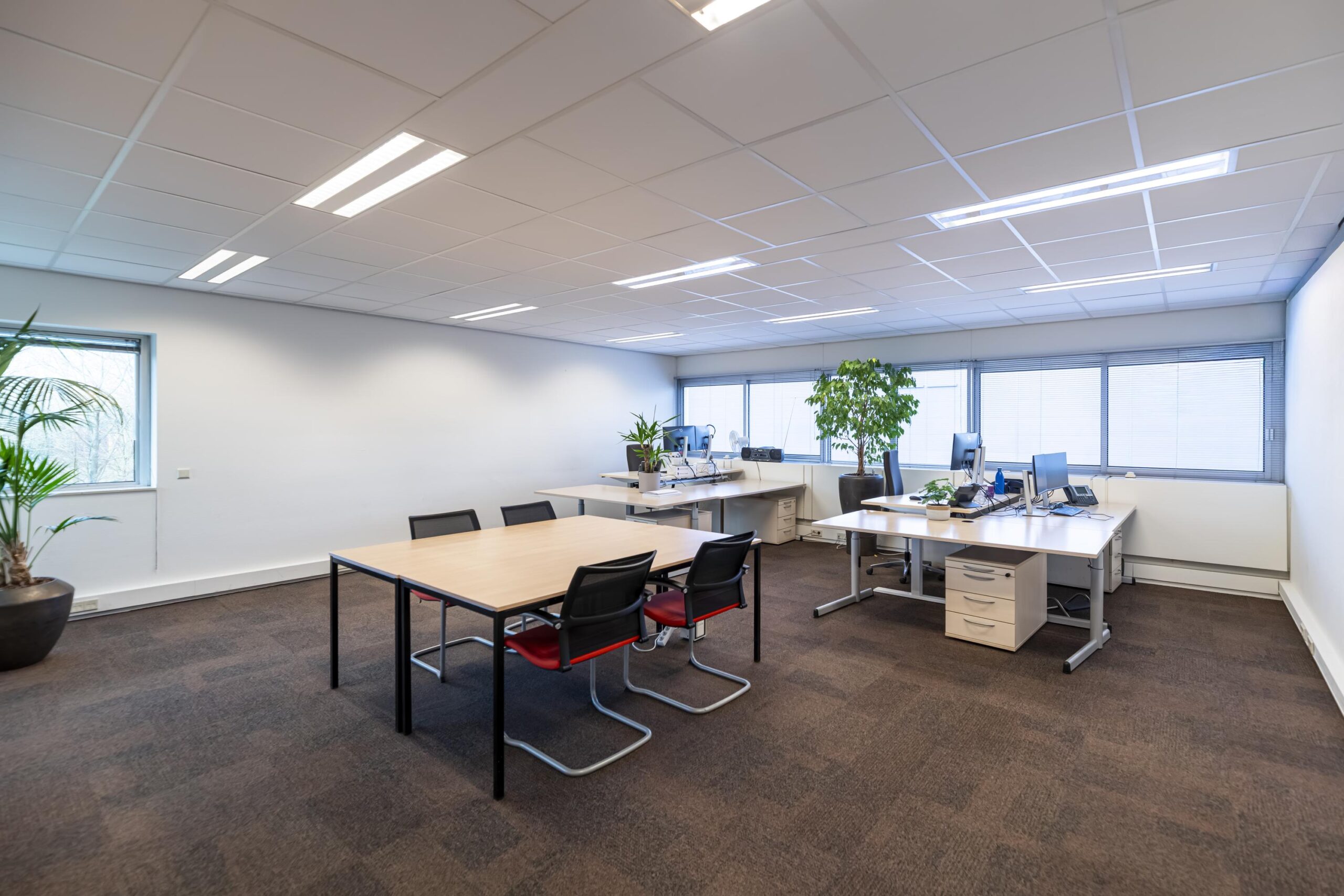 Modern kantoor met meerdere bureaus, vergadertafel en grote ramen aan de Seattleweg.