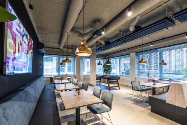 Moderne bedrijfsruimte met zithoeken, een tafelvoetbaltafel en grote ramen die uitzicht bieden op de stad.