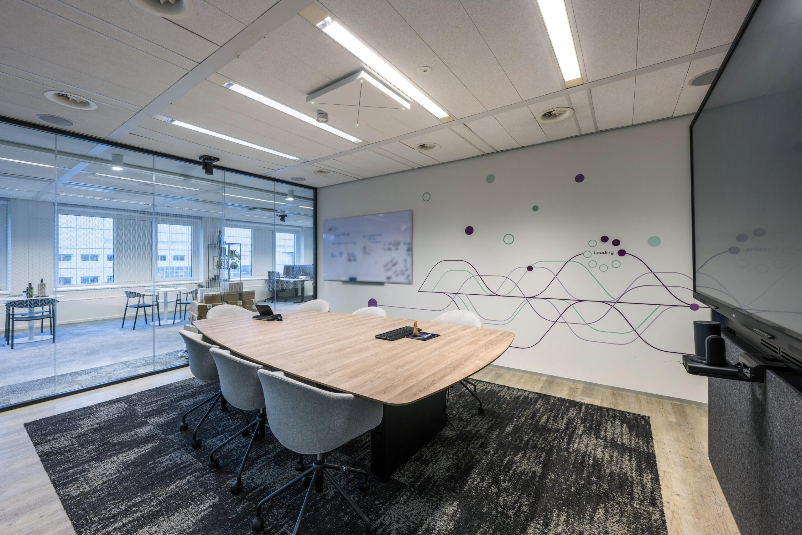 Moderne vergaderruimte met houten tafel, ergonomische stoelen, glazen wanden en een creatieve muurdecoratie met paarse en groene lijnen.