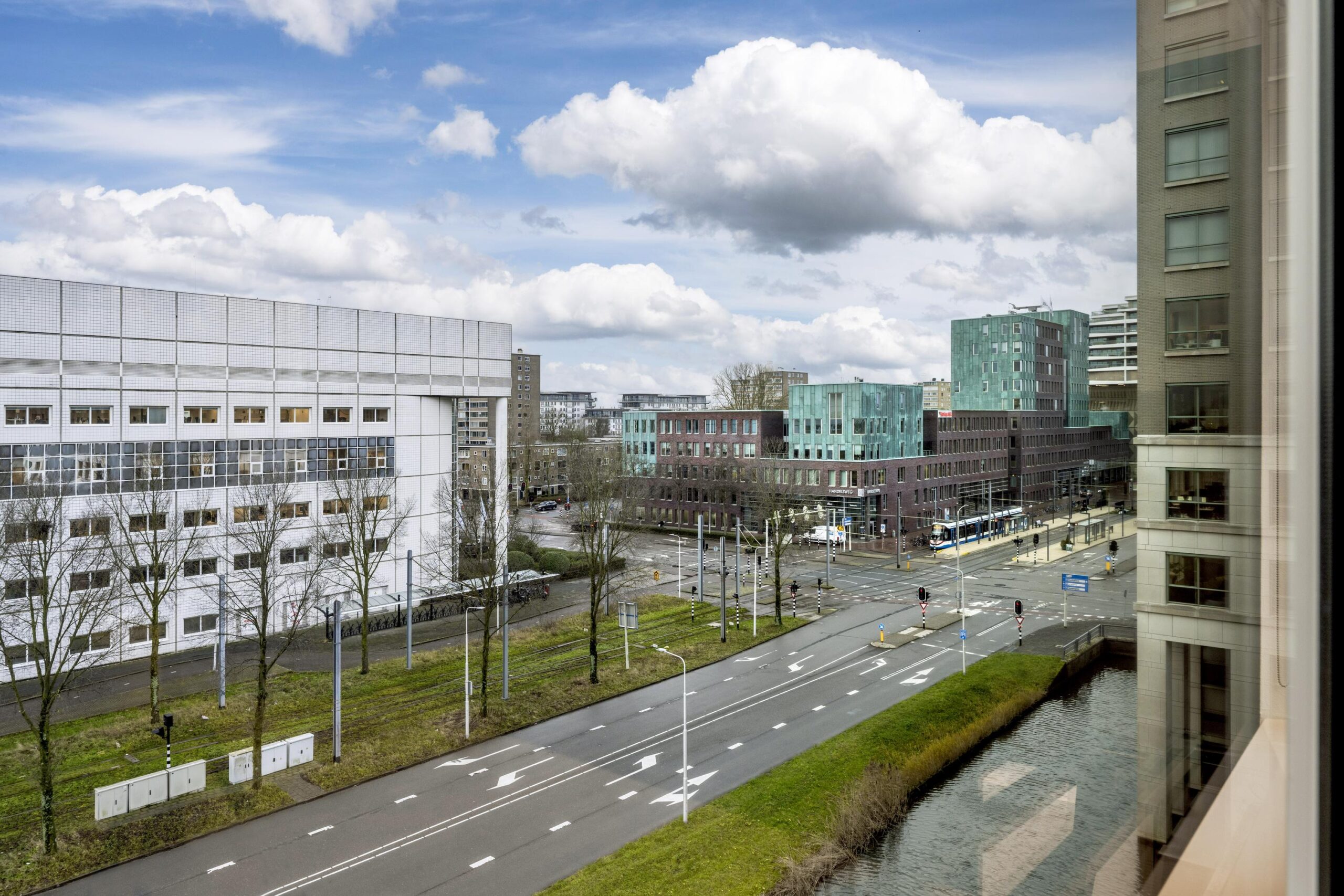 Stadsgezicht op de Stroombaan in Amstelveen met moderne gebouwen, een trambaan en een kruispunt.