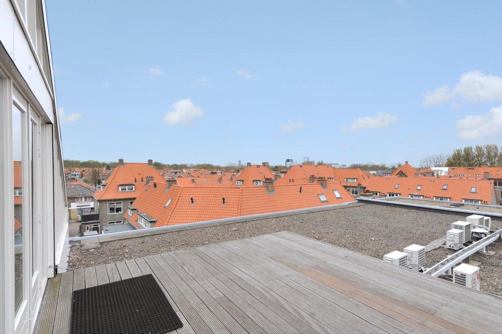 Dakterras met houten vlonder en uitzicht op een wijk met rode dakpannen in Oosteinde.