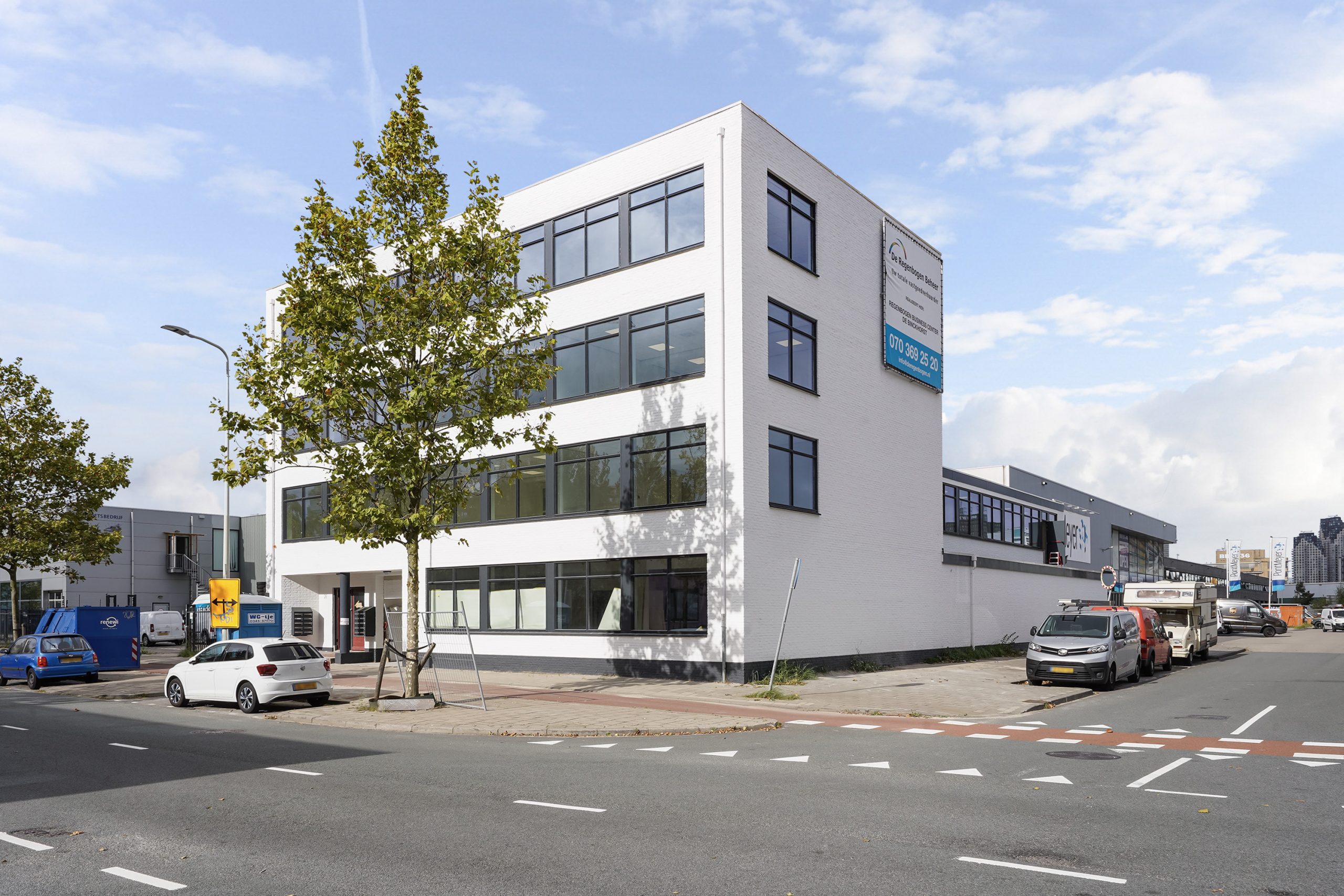 Wit kantoorgebouw aan de Mercuriusweg met meerdere geparkeerde auto’s en een duidelijke bedrijfsreclame aan de gevel.