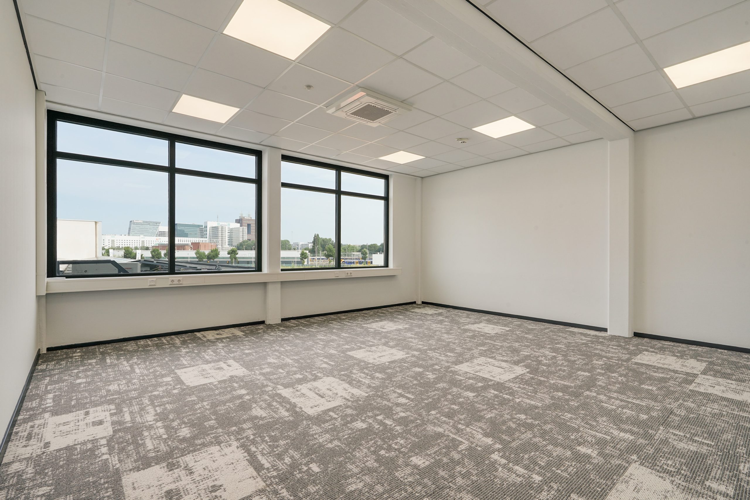 Lichte, lege kantoorruimte aan de Mercuriusweg met groot raam en uitzicht op moderne kantoorgebouwen.