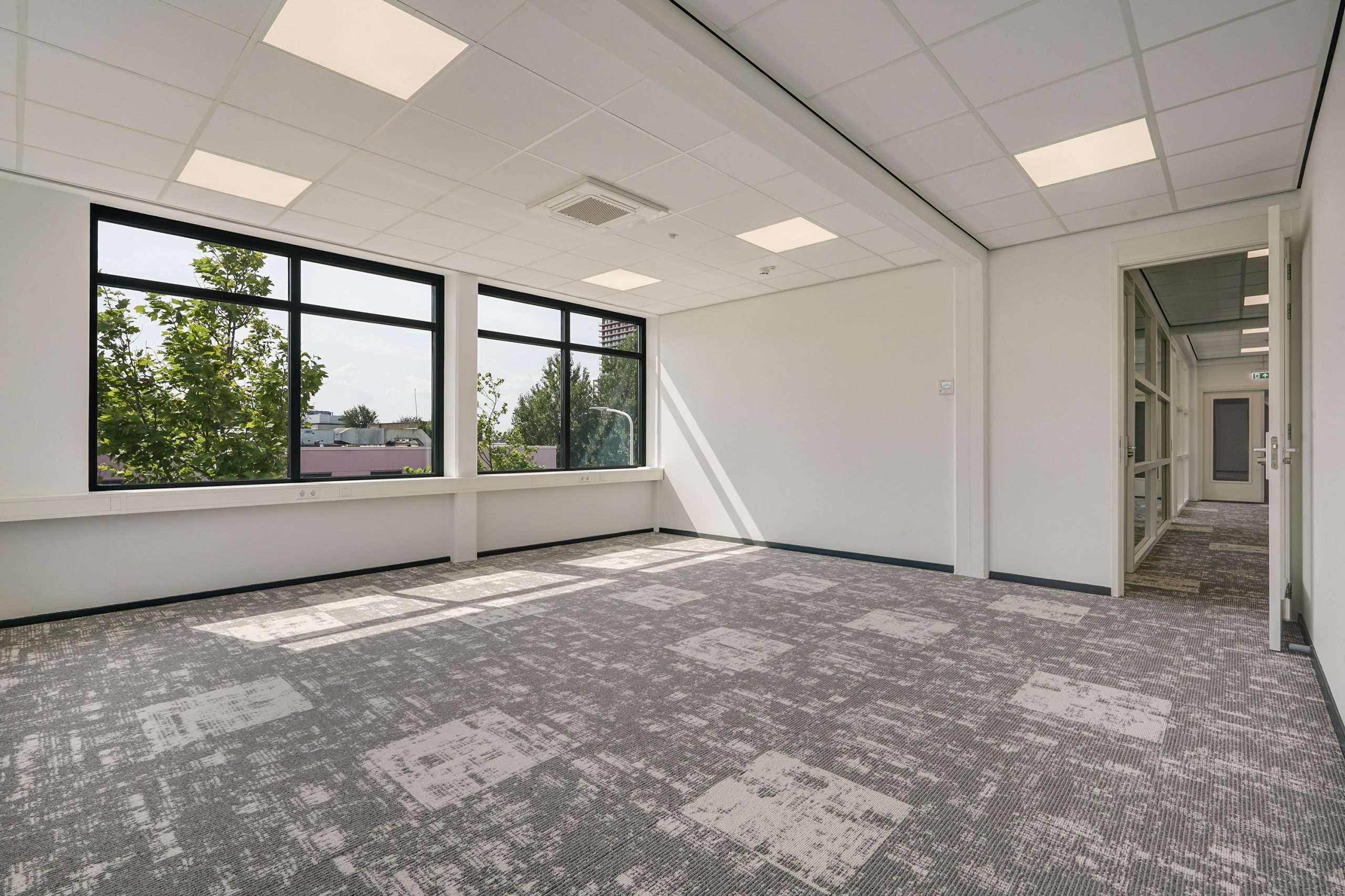 Lichte, lege kantoorruimte aan de Mercuriusweg met grote ramen en modern tapijt.