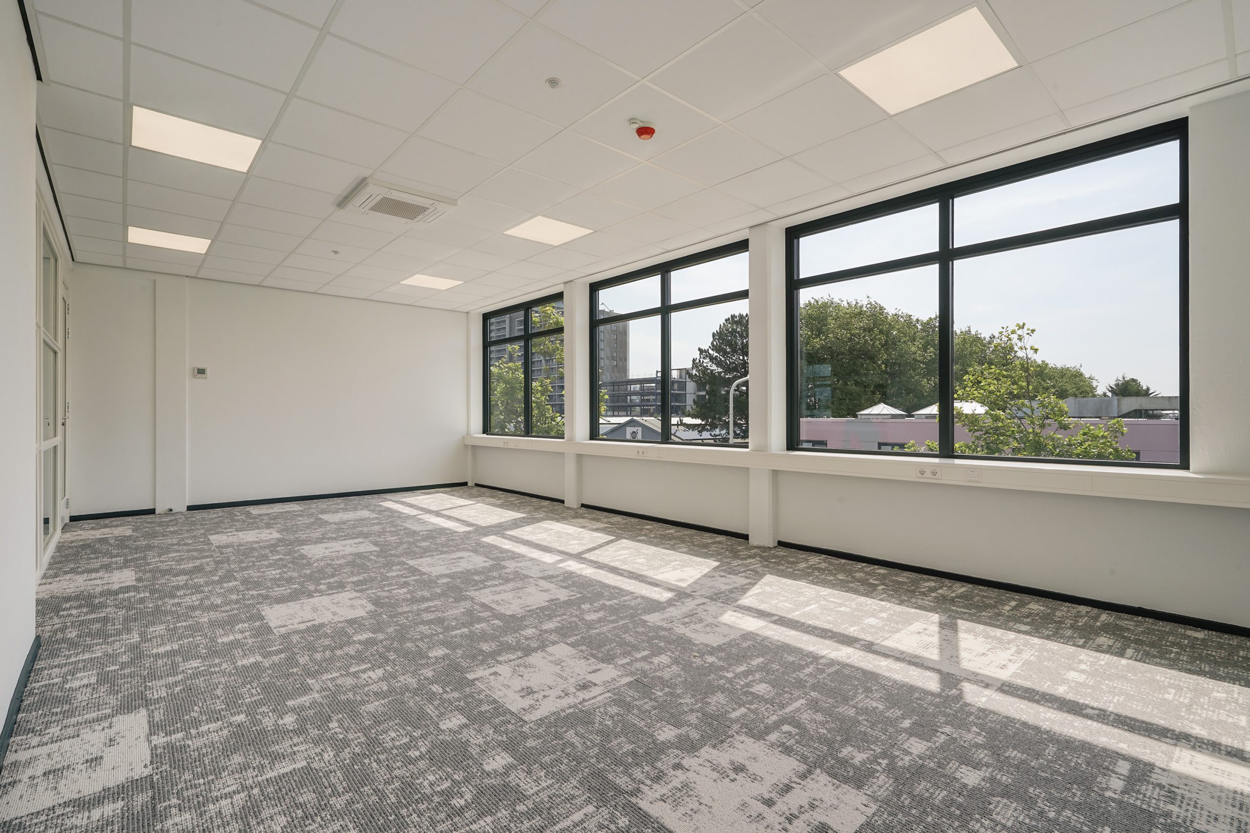 Lichte, lege kantoorruimte aan de Mercuriusweg met grote ramen en modern tapijt.